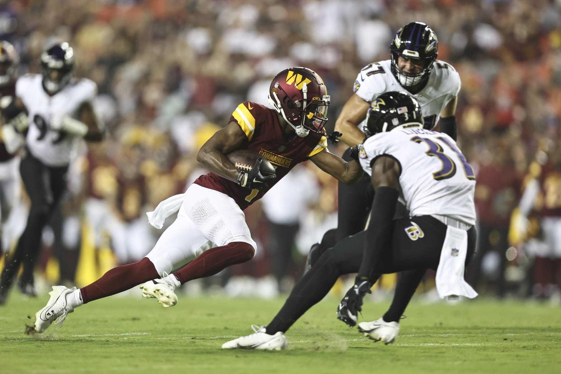 LANDOVER, MARYLAND - AUGUST 21: Jahan Dotson #1 of the Washington Commanders runs with the ball against Jeremy Lucien #31 of the Baltimore Ravens during an NFL preseason game at FedExField on August 21, 2023 in Landover, Maryland. (Photo by Michael Owens/Getty Images)
