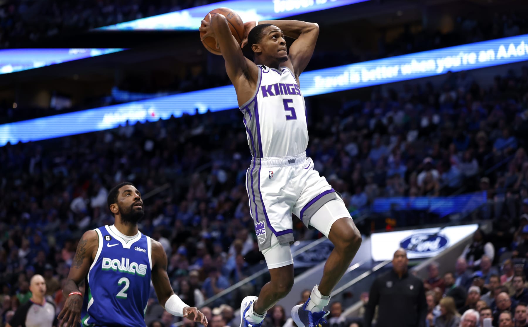 DALLAS, TX - APRIL 5: DeAaron Fox #5 of the Sacramento Kings scores on a break away slam dunk as Kyrie Irving #2 of the Dallas Mavericks looks on in the first half at American Airlines Center on April 5, 2023 in Dallas, Texas. NOTE TO USER: User expressly acknowledges and agrees that, by downloading and or using this photograph, User is consenting to the terms and conditions of the Getty Images License Agreement. (Photo by Ron Jenkins/Getty Images)