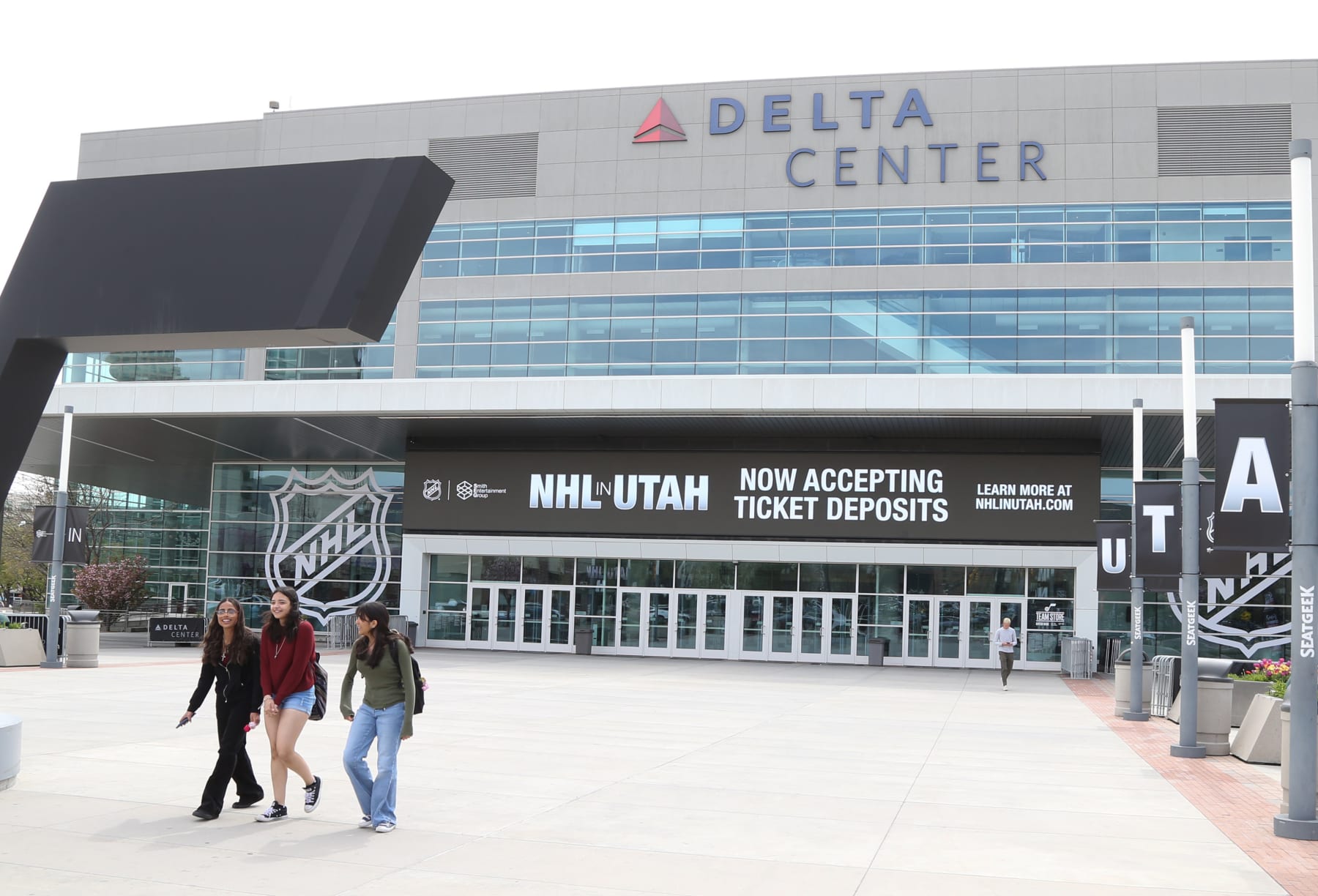 SALT LAKE CITY, UT - APRIL 19: People walk past the main entrance of the Delta Center with the "NHL in Utah" logos on April 19, 2024 in Salt Lake City, Utah.  The NHL has allowed the sale of the Arizona Coyotes and the team will relocate to Salt Lake City, Utah. (Photo by Chris Gardner/Getty Images)