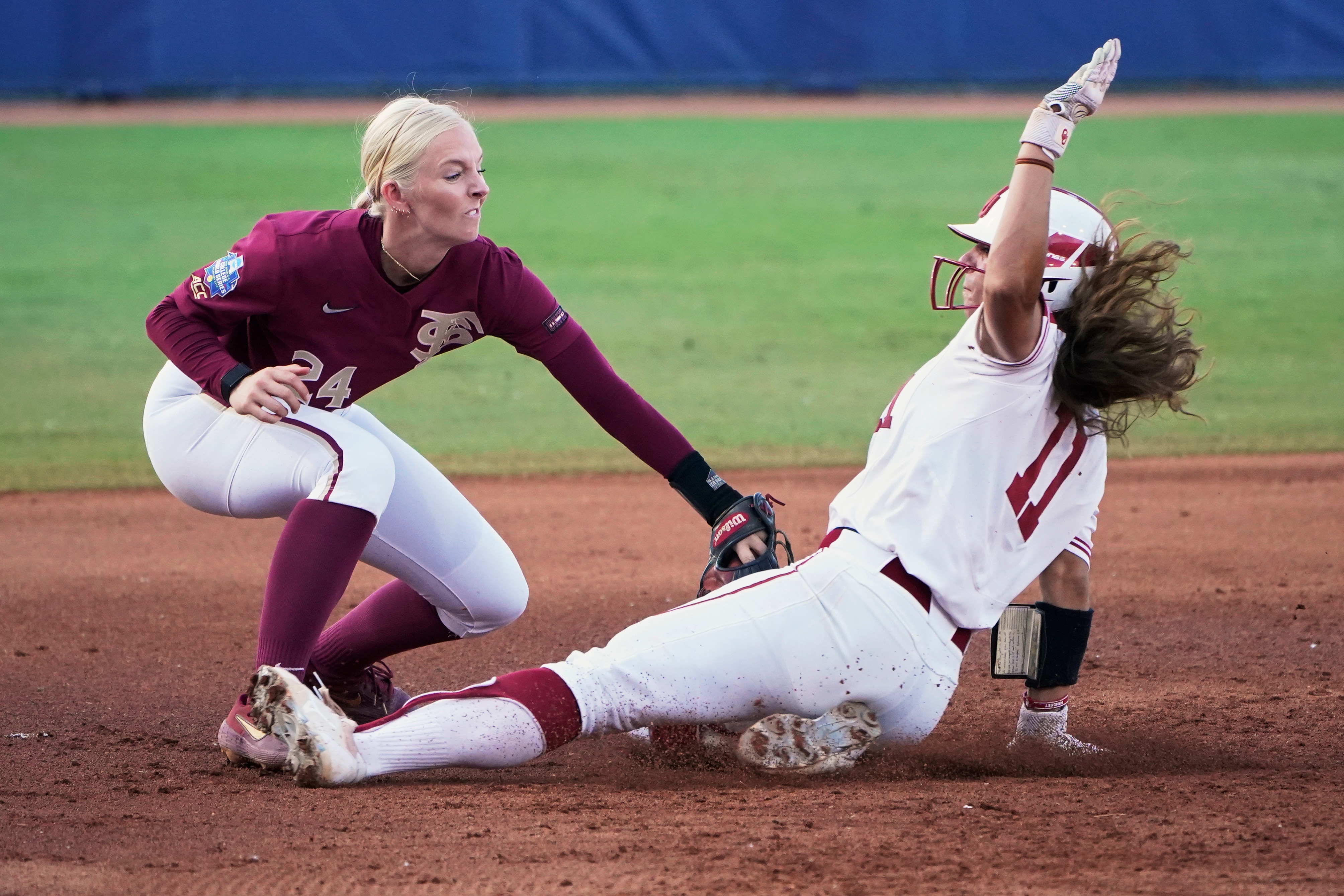 Florida State third baseman Sydney Sherrill, left, tags out Oklahoma's Nicole Mendes (11) during the second inning the first game of the NCAA Women's College World Series softball championship series Tuesday, June 8, 2021, in Oklahoma City. (AP Photo/Sue Ogrocki)
