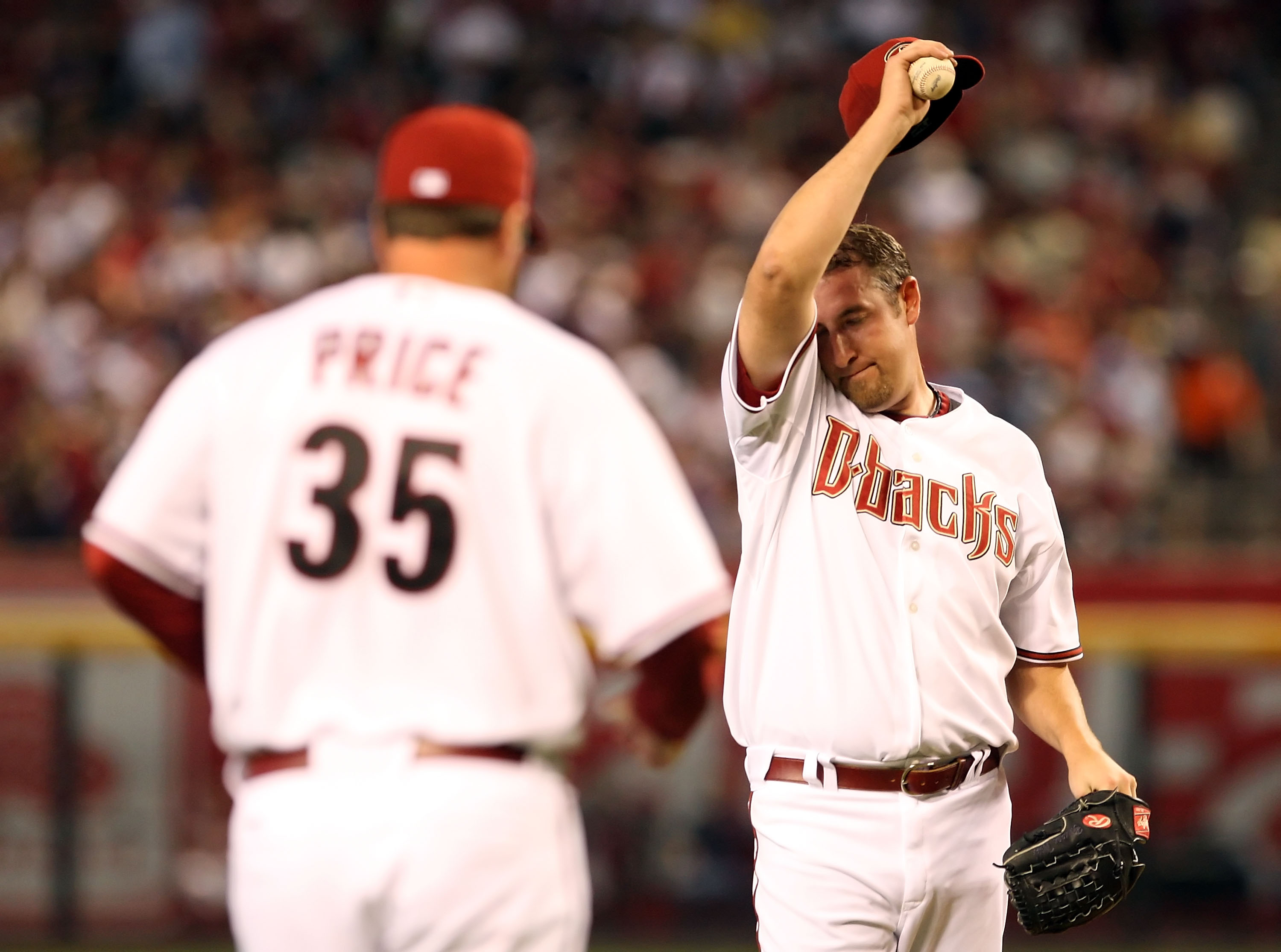 PHOENIX - APRIL 06:  Starting pitcher Brandon Webb #17 of the Arizona Diamondbacks wipes up his face as pitching coach Bryan Price #35 approaches the mound during the MLB openning day game against the Colorado Rockies at Chase Field on April 6, 2009 in Ph