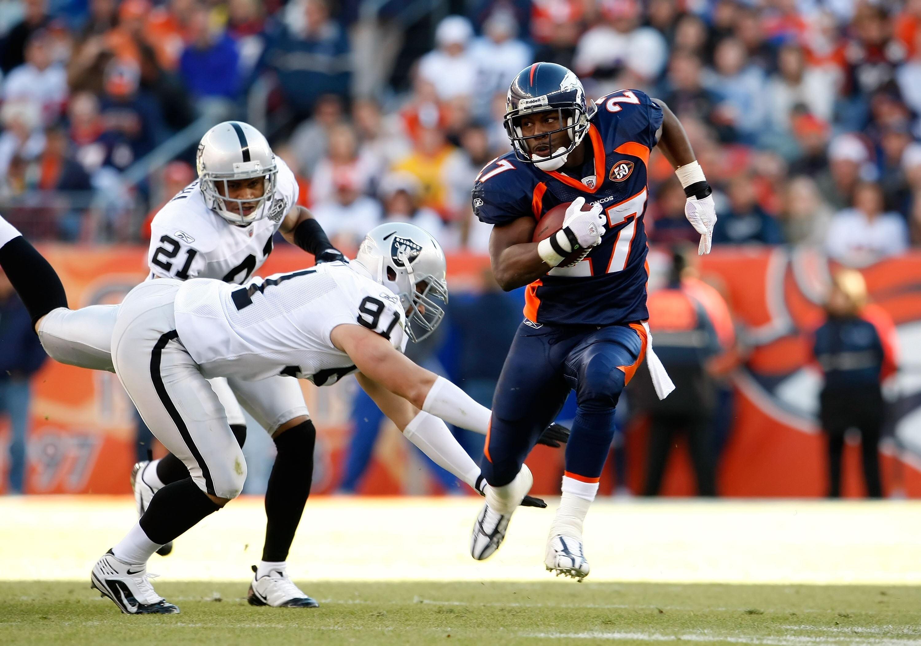 DENVER - DECEMBER 20:  Runningback Knowshon Moreno #27 of the Denver Broncos avoids a tackle from Trevor Scott #91 of the Oakland Raiders in the first half at Invesco Field at Mile High on December 20, 2009 in Denver, Colorado. The Raiders defeated the Br