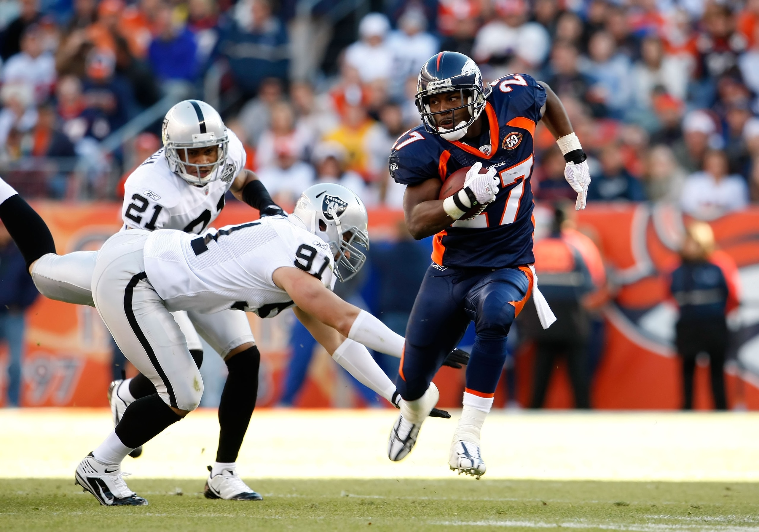 DENVER - DECEMBER 20:  Runningback Knowshon Moreno #27 of the Denver Broncos avoids a tackle from Trevor Scott #91 of the Oakland Raiders in the first half at Invesco Field at Mile High on December 20, 2009 in Denver, Colorado. The Raiders defeated the Br