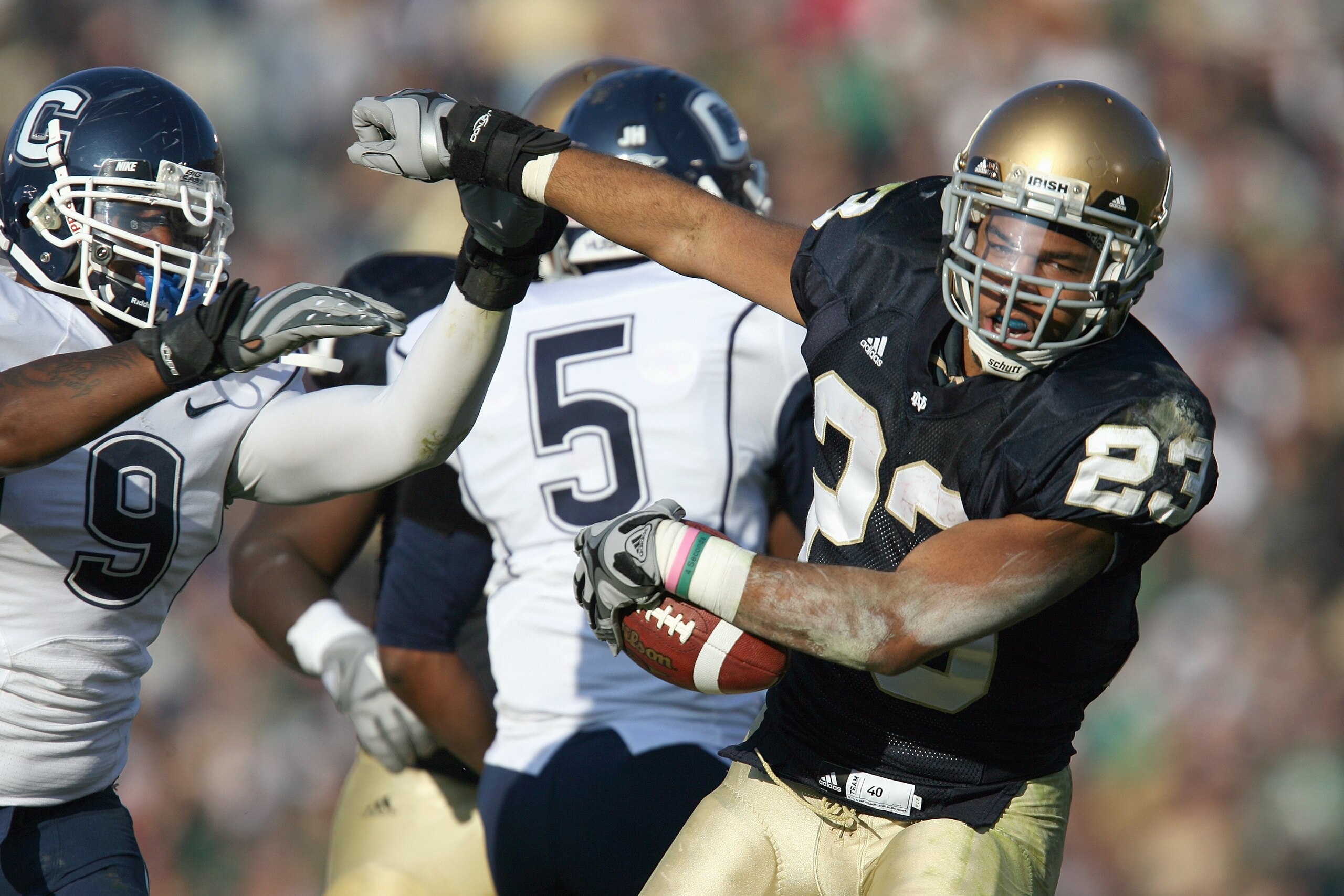 SOUTH BEND, IN - NOVEMBER 21: Golden Tate #23 of the Notre Dame Fighting Irish carries the ball as he is grabbed by Lindsay Witten #9 of the Univeristy of Connecticut Huskies at Notre Dame Stadium on November 21, 2009 in South Bend, Indiana. (Photo by Jon
