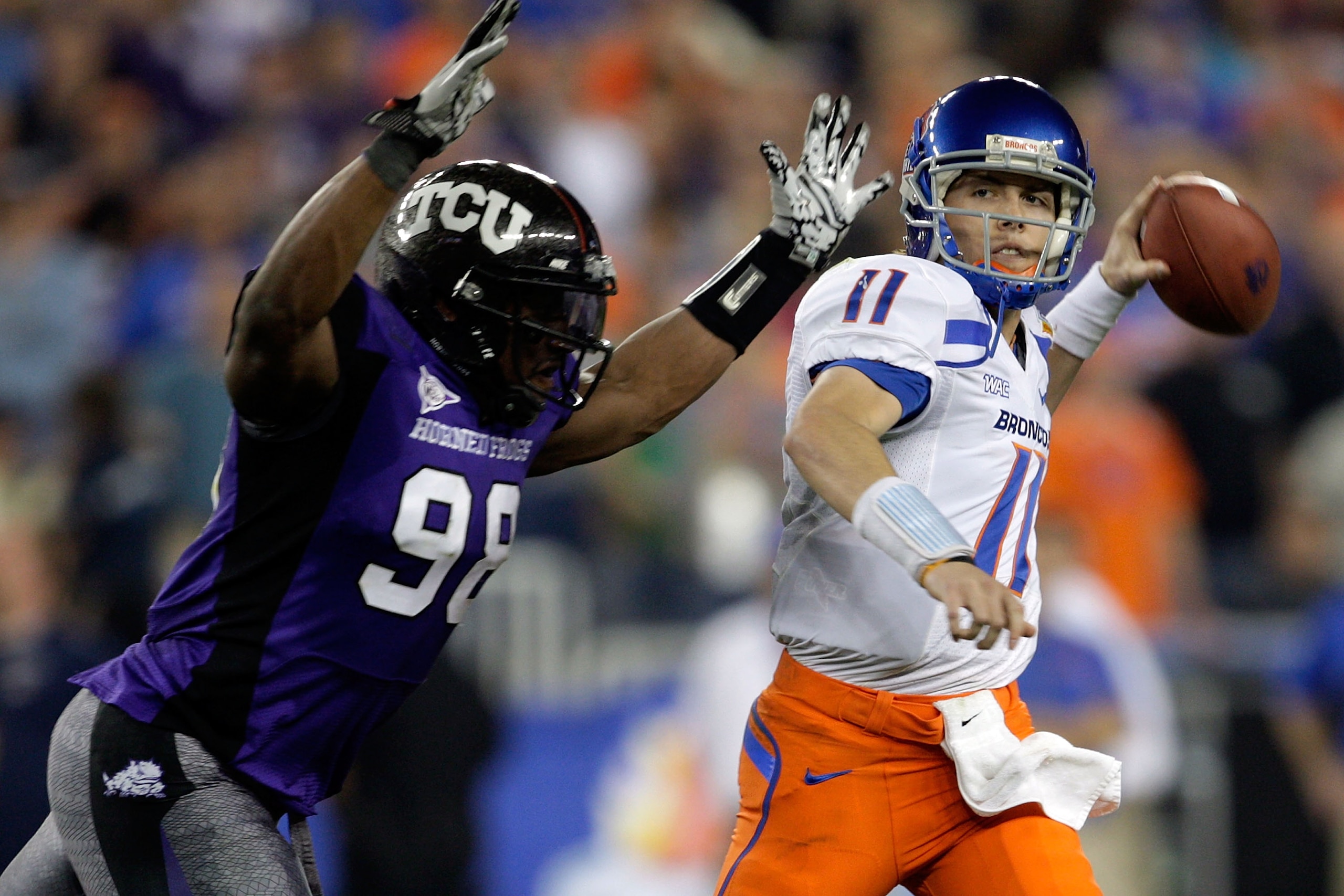 GLENDALE, AZ - JANUARY 04:  Quarterback Kellen Moore #11 of the Boise State Broncos passes the ball in the first half as he is hit by Jerry Hughes #98 of the TCU Horned Frogs during the Tostitos Fiesta Bowl at the Universtity of Phoenix Stadium on January