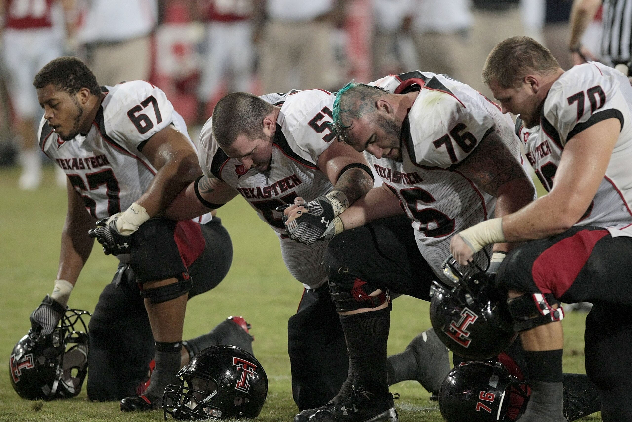 HOUSTON - SEPTEMBER 26: Marlon Winn #67 , Shawn Byrnes 51, Brandon Carter 76, and Chris Olson 70 of the Texas Tech Red Raiders pray for a hurt University of Houston player at Robertson Stadium on September 26, 2009 in Houston, Texas.  (Photo by Thomas B.