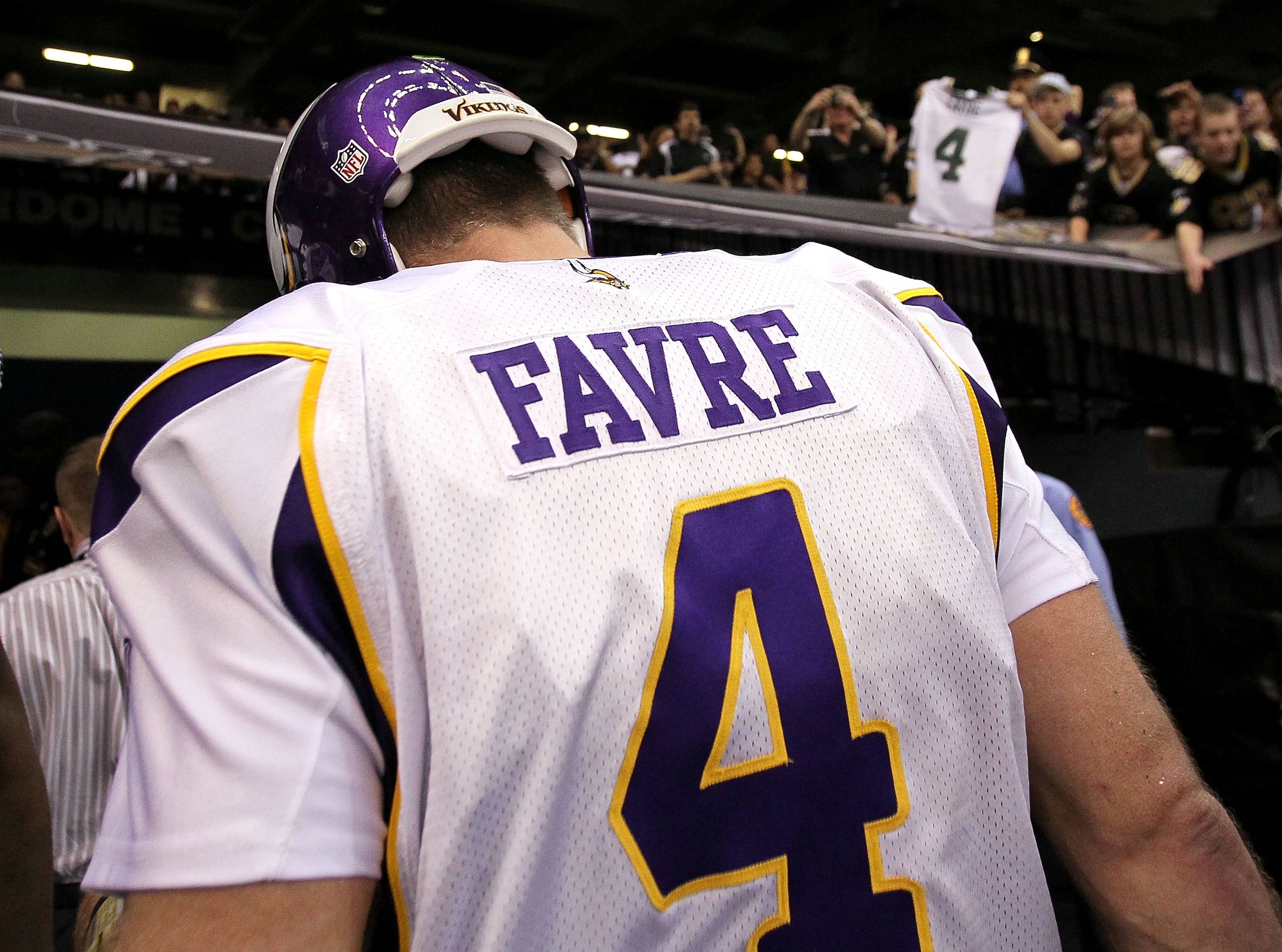 NEW ORLEANS - JANUARY 24:  A fan in the stands holds up a Green Bay Packers #4 jersey as Brett Favre #4 of the Minnesota Vikings walks off the field after the Vikings lost to the New Orleans Saints 31-28 in overtime during the NFC Championship Game at the
