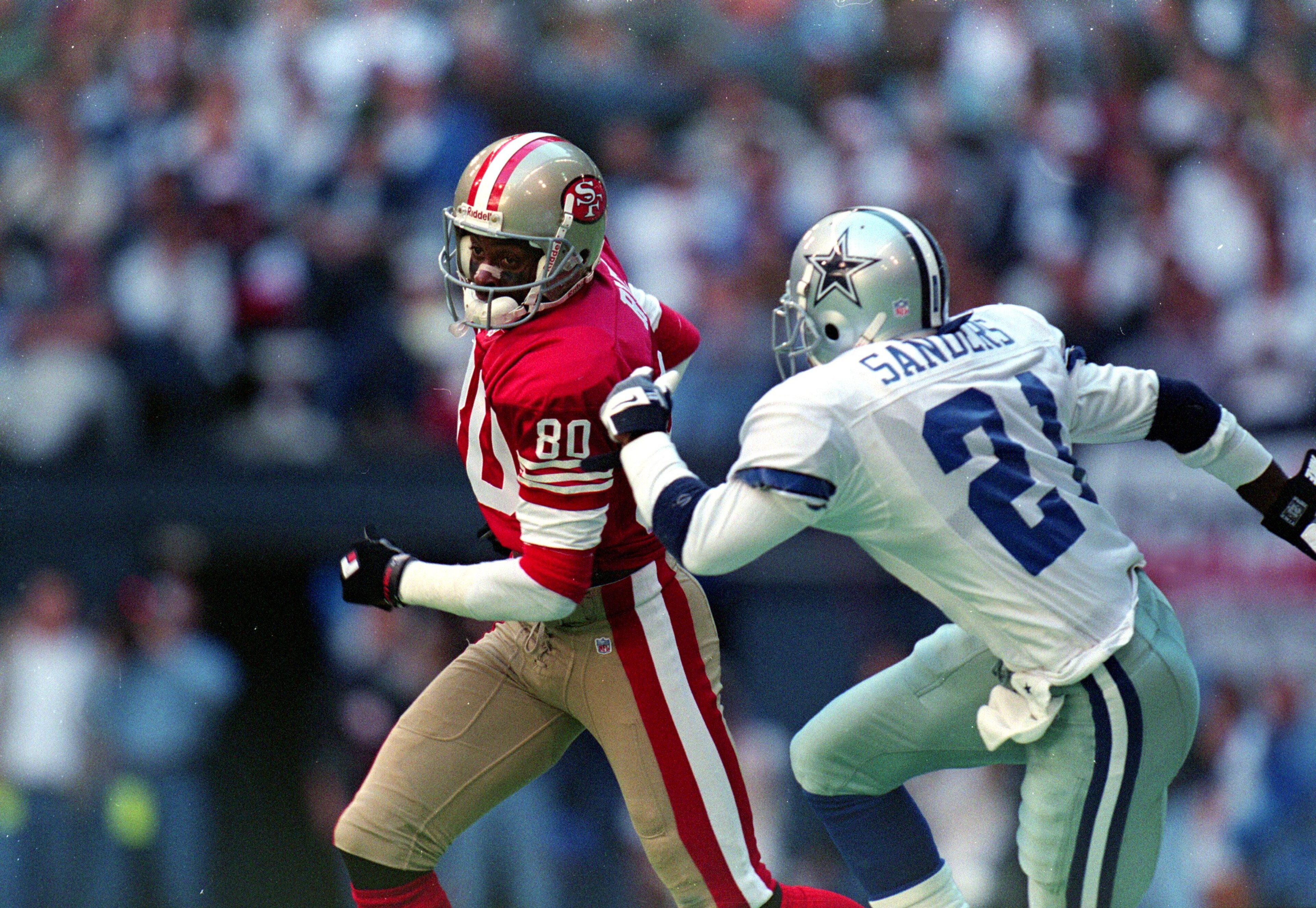 12 Nov 1995: Jerry Rice #80 of the San Francisco 49ers runs with the ball as Deion Sanders #21 of the Dallas Cowboys runs after him during the game at the Texas Stadium in Irving, Texas. The 49ers defeated the Cowboys 38-20. 12 Nov 1995: Jerry Rice #80 of the San Francisco 49ers runs with the ball as Deion Sanders #21 of the Dallas Cowboys runs after him during the game at the Texas Stadium in Irving, Texas. The 49ers defeated the Cowboys 38-20.