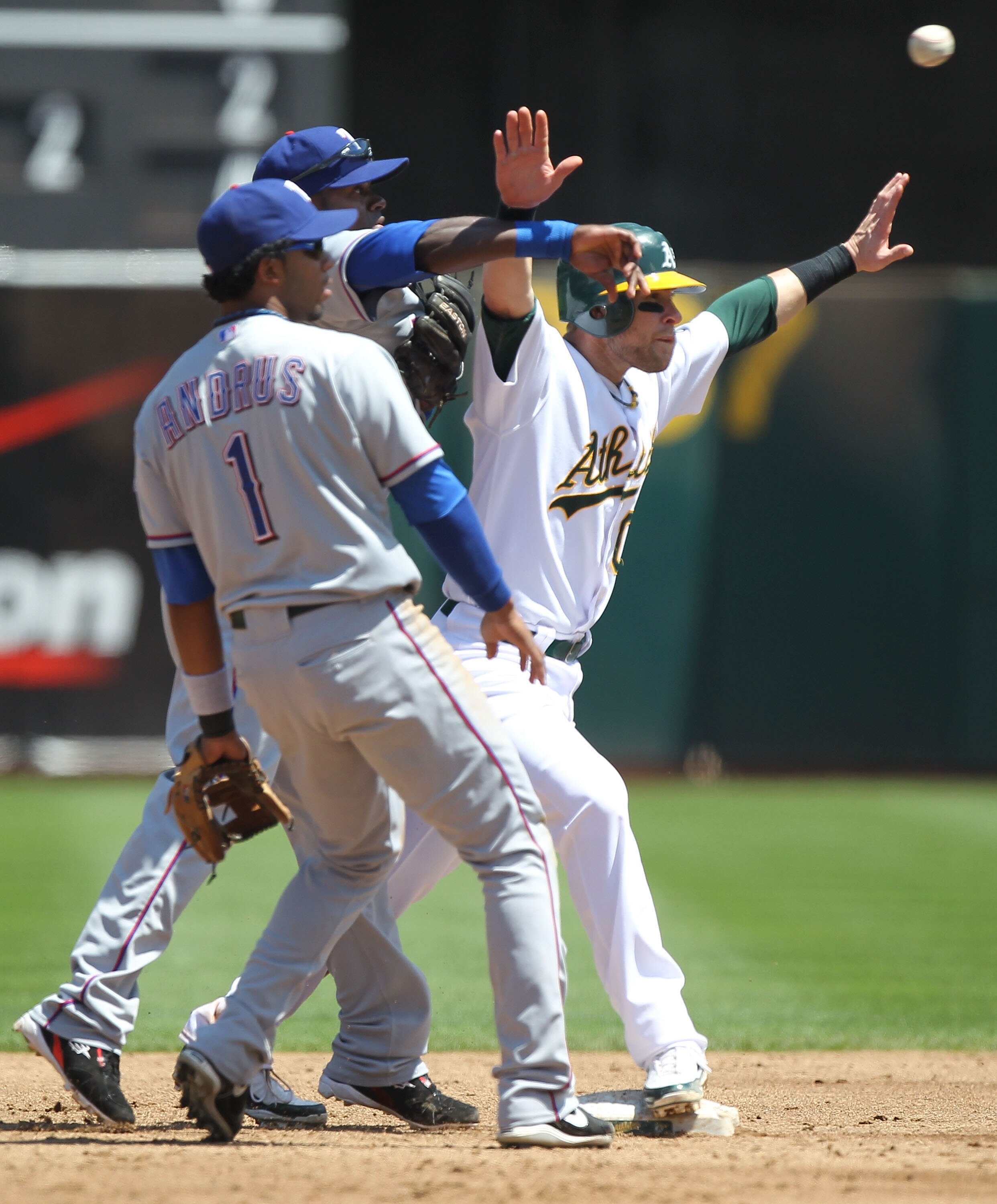 OAKLAND, CA - AUGUST 08:  Daric Barton #10 of the Oakland Athletics is safe at second as Cristian Guzman #12 of the Texas Rangers throws to first on a fielders choice hit by Kurt Suzki as Elvis Andrus #1 looks on in the third inning during an MLB game at