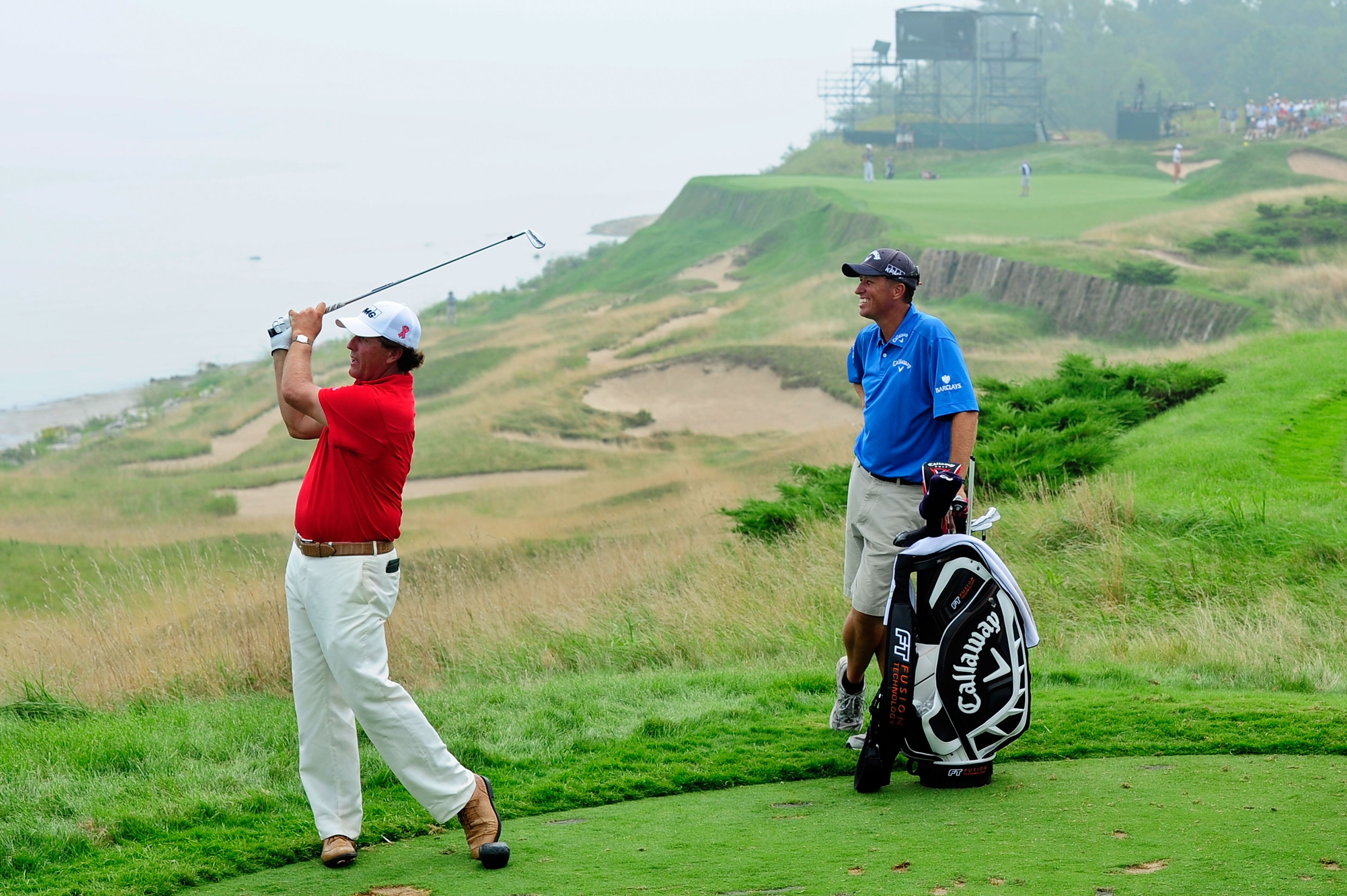 KOHLER, WI - AUGUST 10:  Phil Mickelson (L) hits a shot while caddie Jim 'Bones' Mackay looks on during a practice round prior to the start of the 92nd PGA Championship on the Straits Course at Whistling Straits on August 10, 2010 in Kohler, Wisconsin.  (