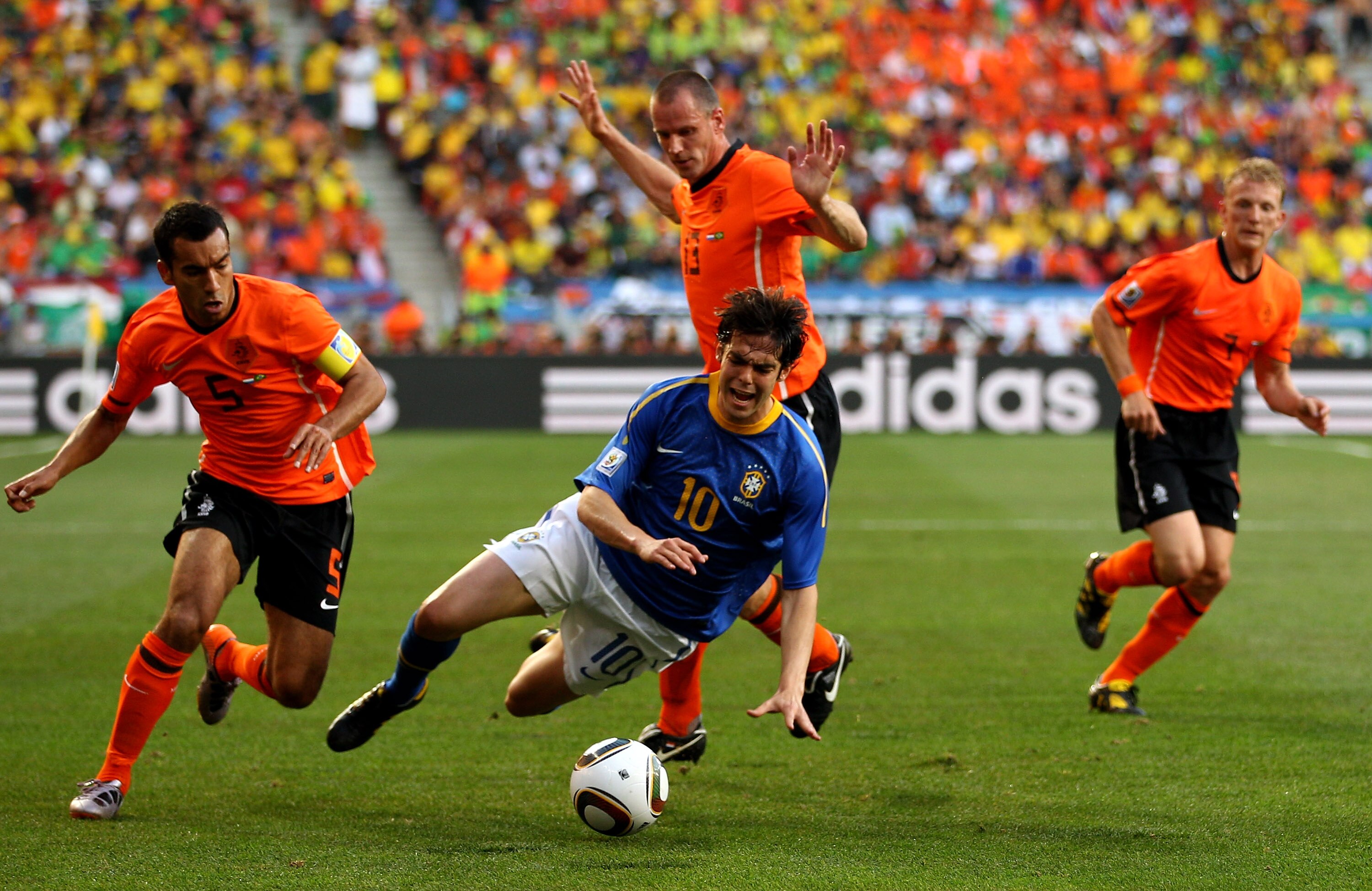 PORT ELIZABETH, SOUTH AFRICA - JULY 02:  Kaka of Brazil is brought down by Giovanni Van Bronckhorst and Andre Ooijer of The Netherlands during the 2010 FIFA World Cup South Africa Quarter Final match between Netherlands and Brazil at Nelson Mandela Bay St
