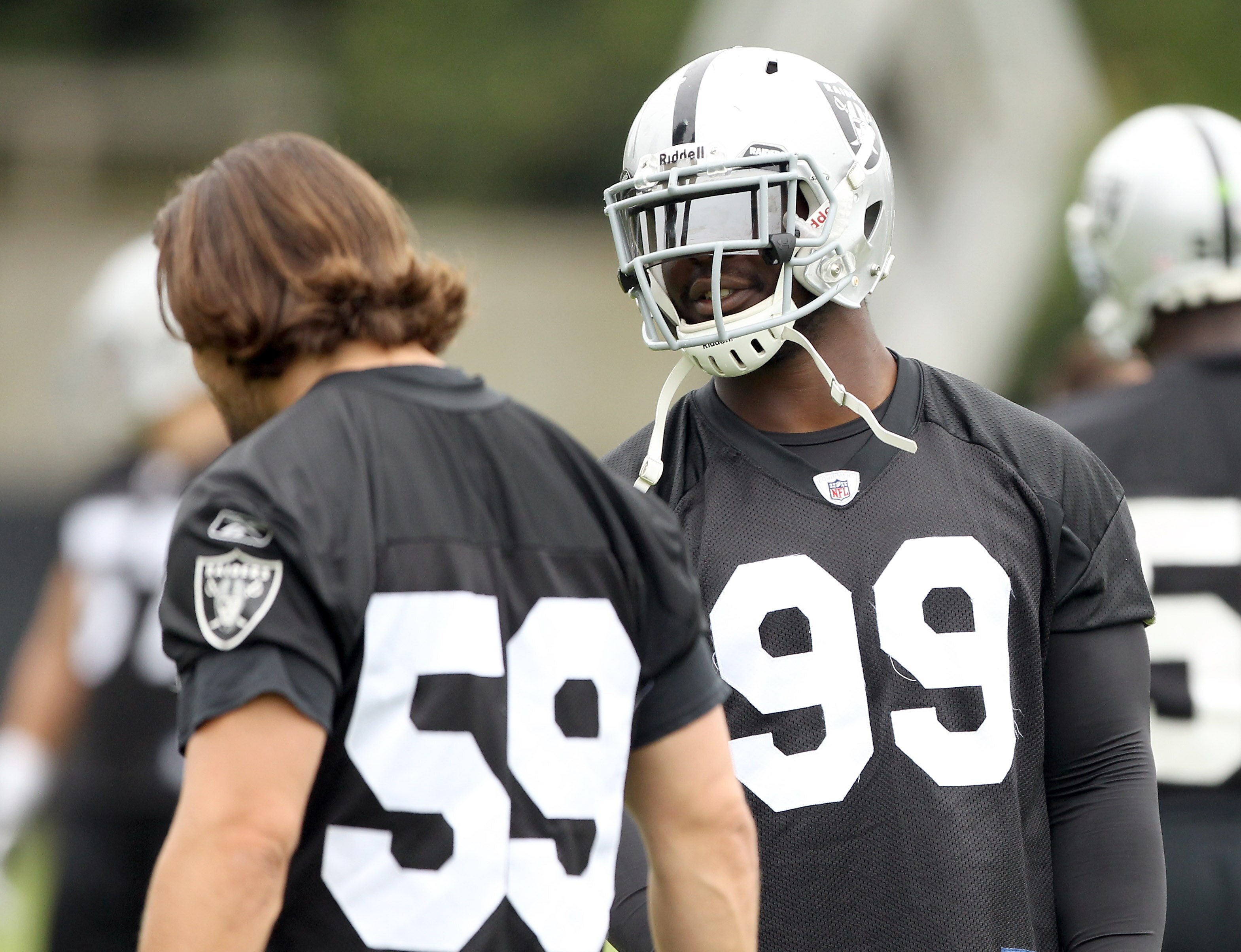 NAPA, CA - AUGUST 01:  Lamarr Houston #99 of the Oakland Raiders talks to Jon Condo #59 during the Raiders training camp at their Napa Valley Training Complex on August 1, 2010 in Napa, California.  (Photo by Ezra Shaw/Getty Images)