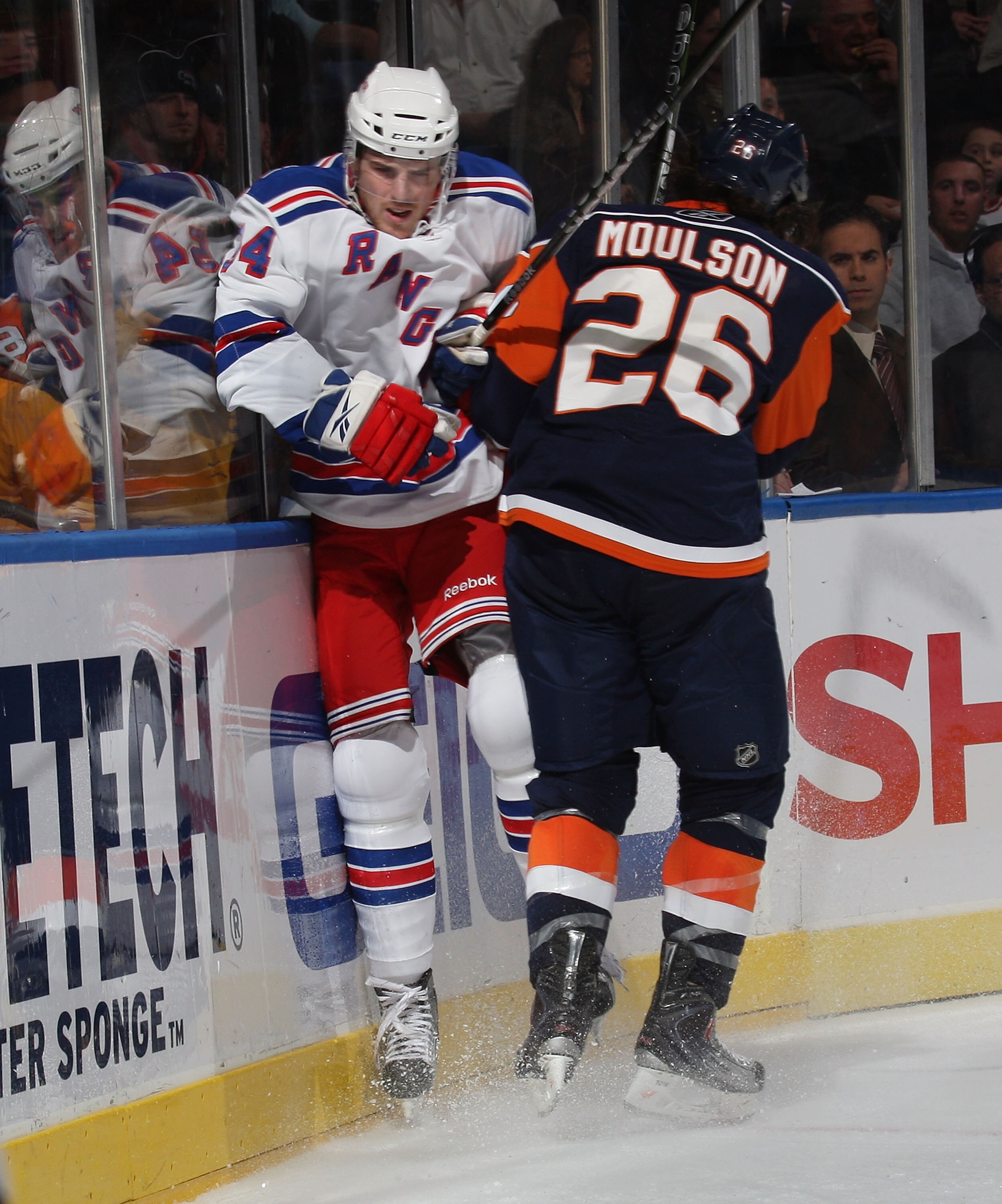 UNIONDALE, NY - DECEMBER 17: Bobby Sanguinetti #54 of the New York Rangers is hit by Matt Moulson #26 of the New York Islanders at the Nassau Coliseum on December 17, 2009 in Uniondale, New York.  (Photo by Bruce Bennett/Getty Images)
