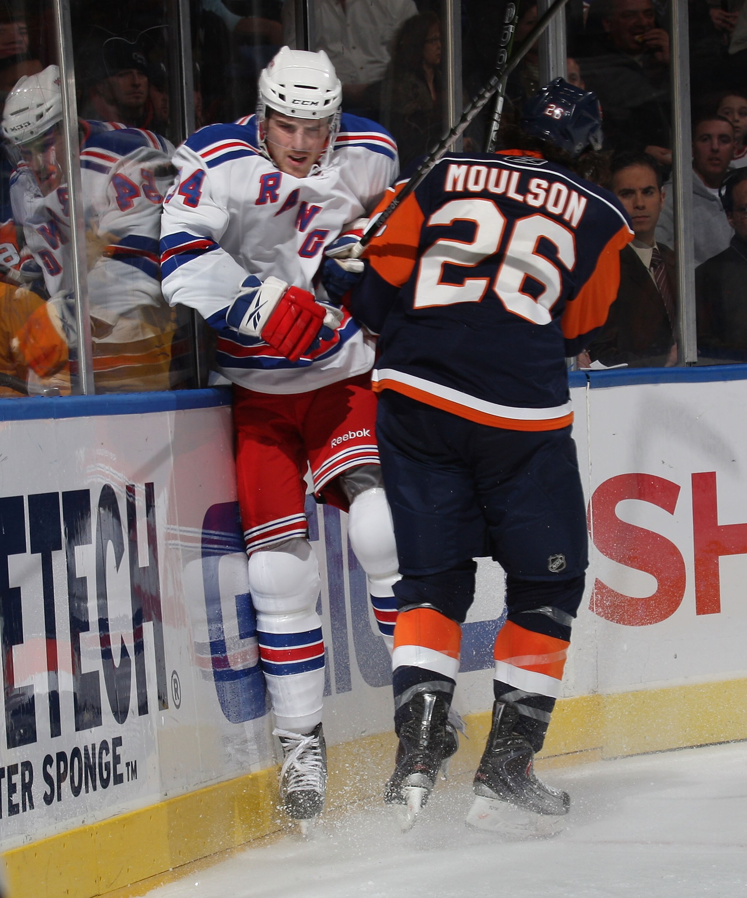 UNIONDALE, NY - DECEMBER 17: Bobby Sanguinetti #54 of the New York Rangers is hit by Matt Moulson #26 of the New York Islanders at the Nassau Coliseum on December 17, 2009 in Uniondale, New York.  (Photo by Bruce Bennett/Getty Images)