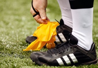 An NFL official retrieves his penalty flag