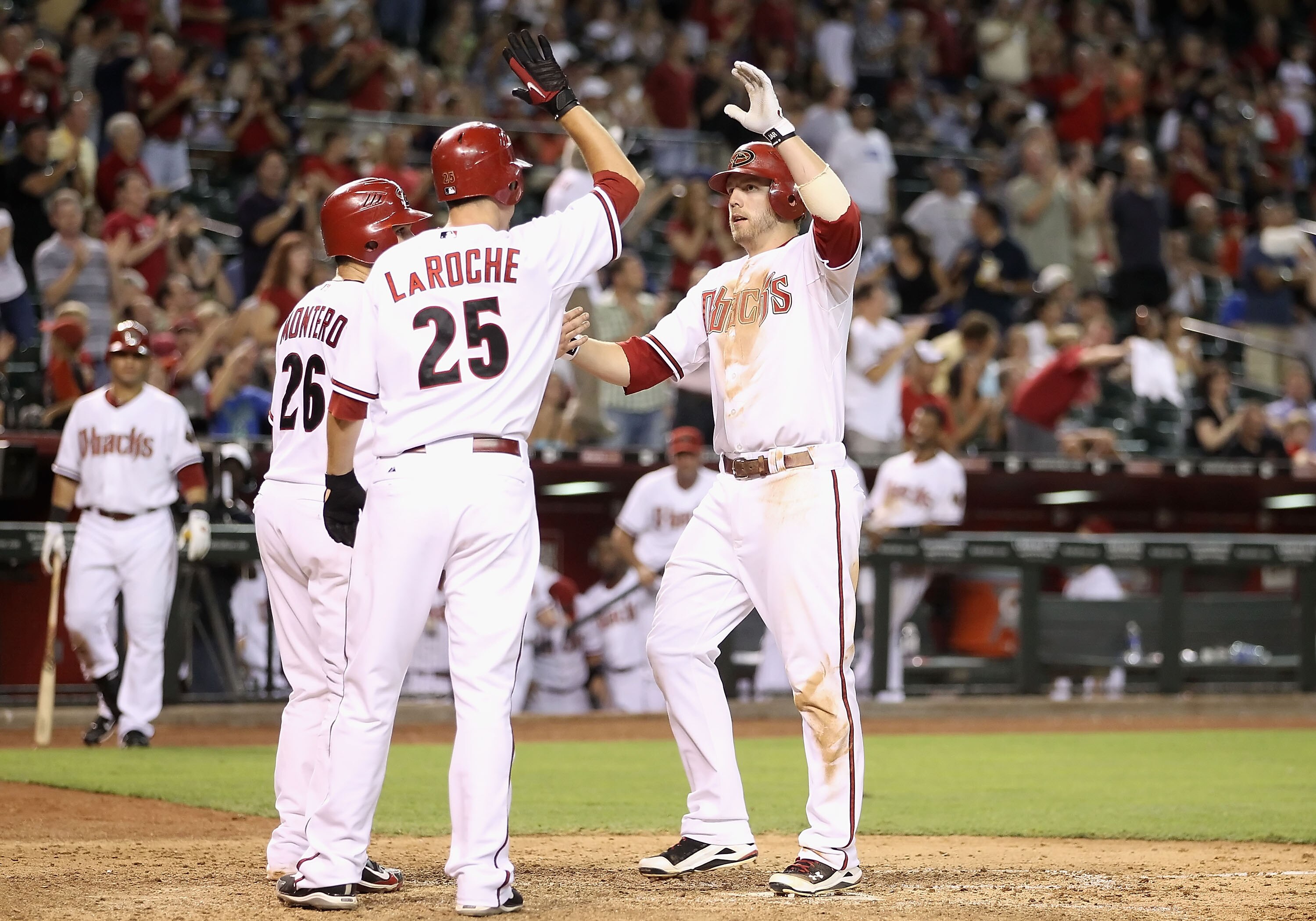 PHOENIX - JULY 19:  Mark Reynolds #27 of the Arizona Diamondbacks is congratulated by teammates Miguel Montero #26 and Adam LaRoche #25 after hitting a 3 run home run against the New York Mets during the sixth inning of the Major League Baseball game at C