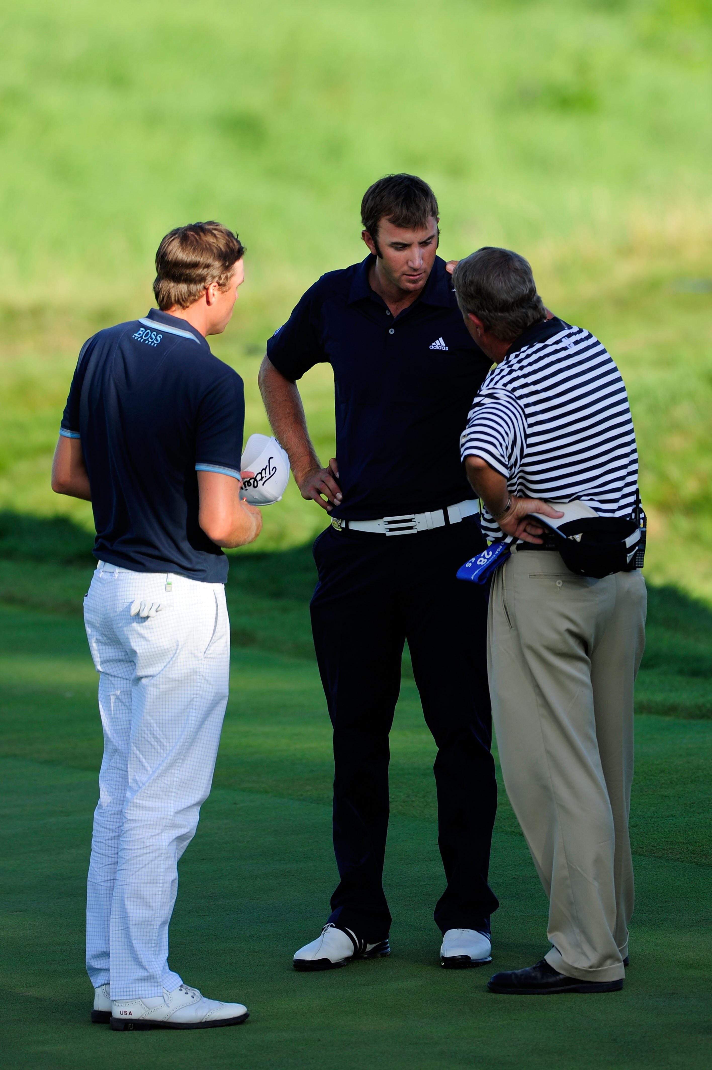 KOHLER, WI - AUGUST 15:  A PGA of America rules official chats with Dustin Johnson (R) on the 18th green as Nick Watney (L) looks on during the final round of the 92nd PGA Championship on the Straits Course at Whistling Straits on August 15, 2010 in Kohle