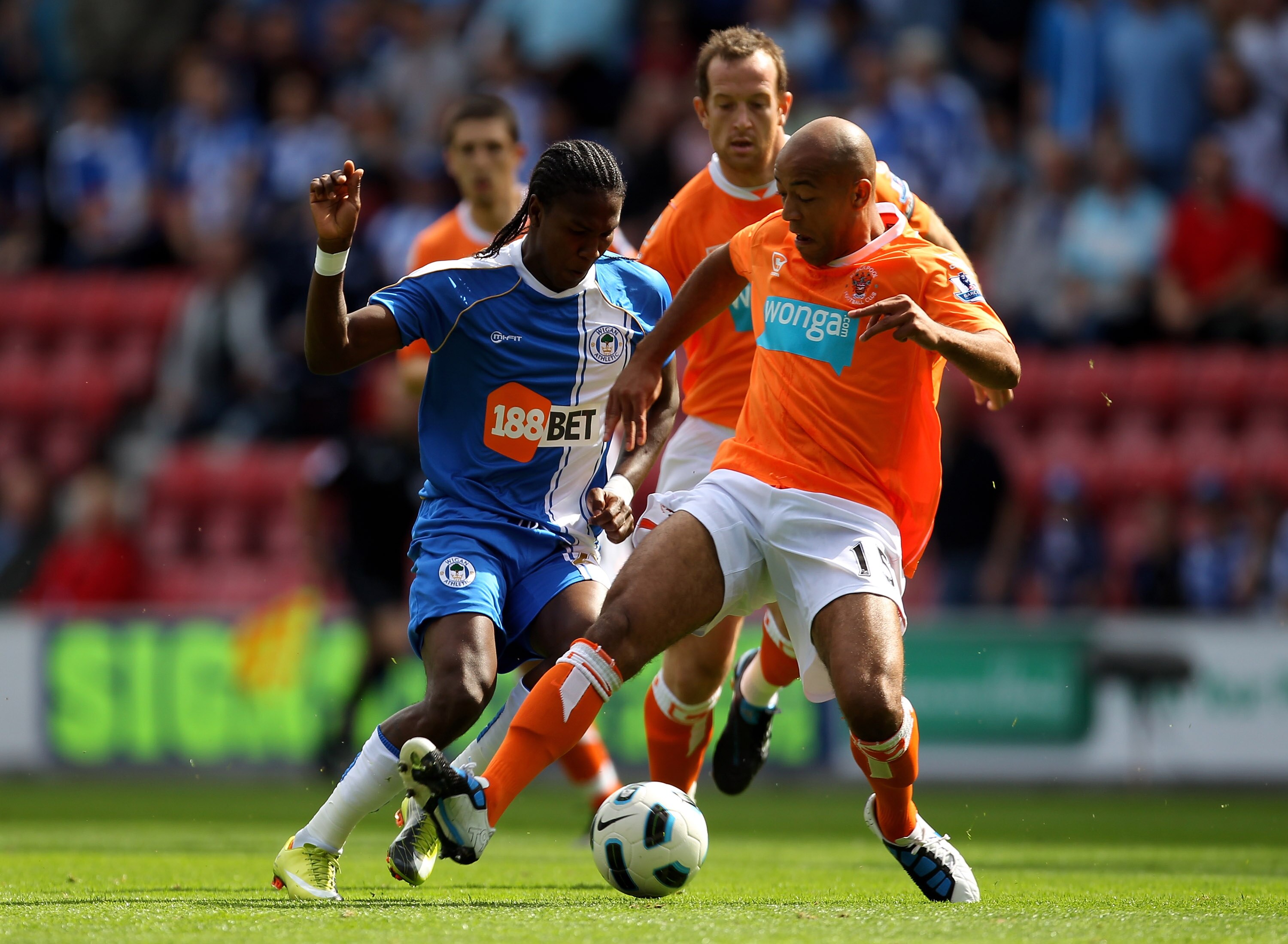 WIGAN, ENGLAND - AUGUST 14:  Hugo Rodallega of Wigan Athletic is challenged by Alex Baptiste of Blackpool during the Barclays Premier League match between Wigan Athletic and Blackpool at the DW Stadium on August 14, 2010 in Wigan, England.  (Photo by Alex