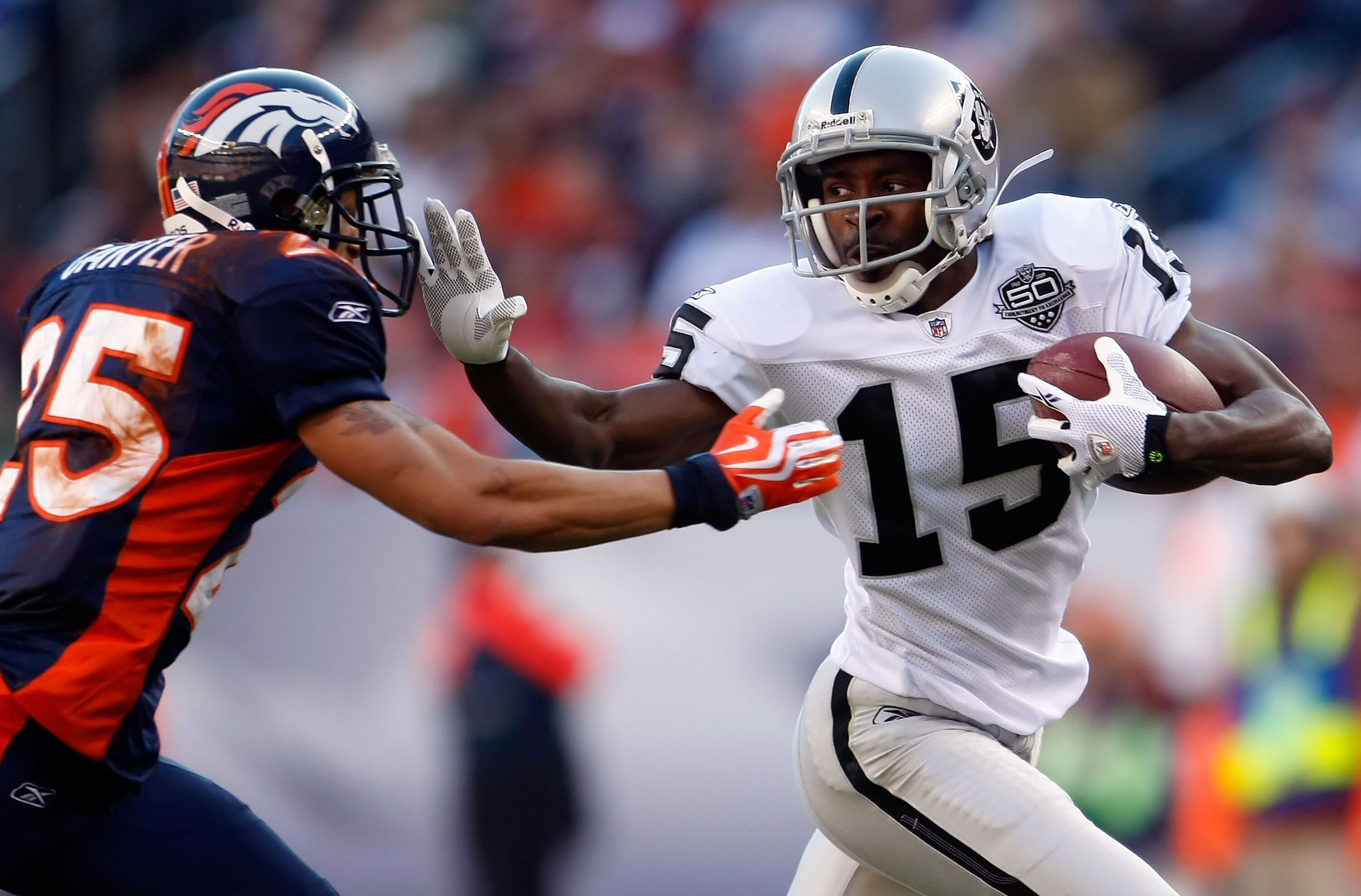 DENVER - DECEMBER 20:  Johnnie Lee Higgins #15 of the Oakland Raiders stiff arms Tony Carter #25 of the Denver Broncos in the first half at Invesco Field at Mile High on December 20, 2009 in Denver, Colorado. The Raiders defeated the Broncos 20-19.  (Phot