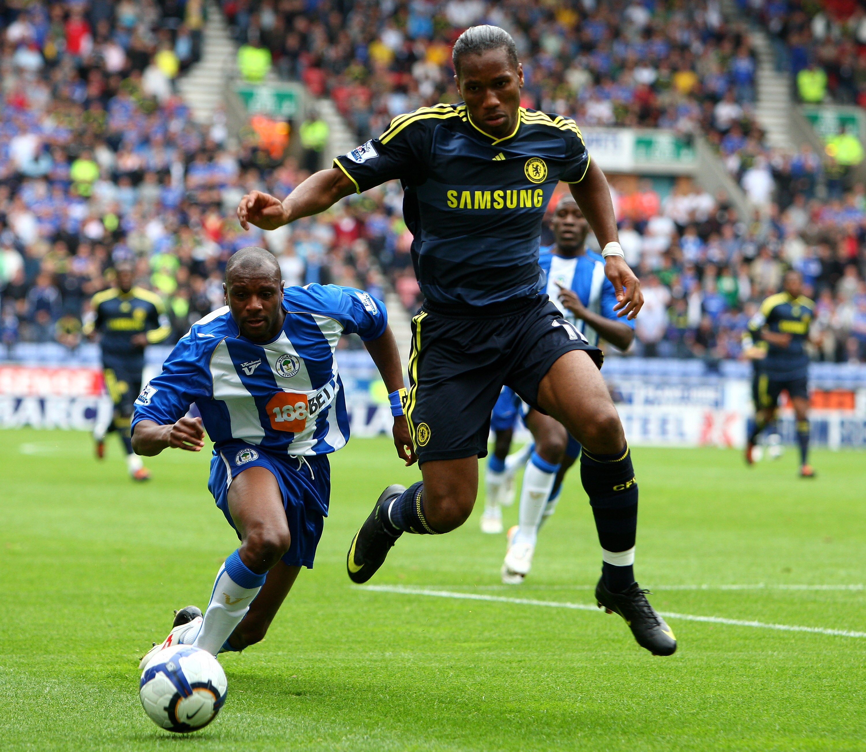 WIGAN, ENGLAND - SEPTEMBER 26:  Didier Drogba of Chelsea gets tackled by Emmerson Boyce of Wigan Athletic during the Barclays Premier League match between Wigan Athletic and Chelseaat DW Stadium on September 26, 2009 in Wigan, England.  (Photo by Phil Col
