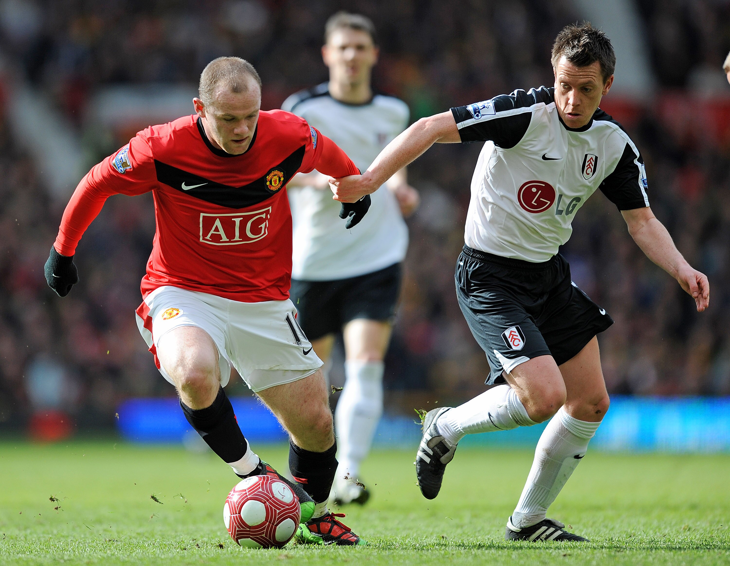 MANCHESTER, ENGLAND - MARCH 14: Wayne Rooney of Manchester United is challenged by Nicky Shorey of Fulham during the Barclays Premier League match between Manchester United and Fulham at Old Trafford on March 14, 2010 in Manchester, England.  (Photo by Mi