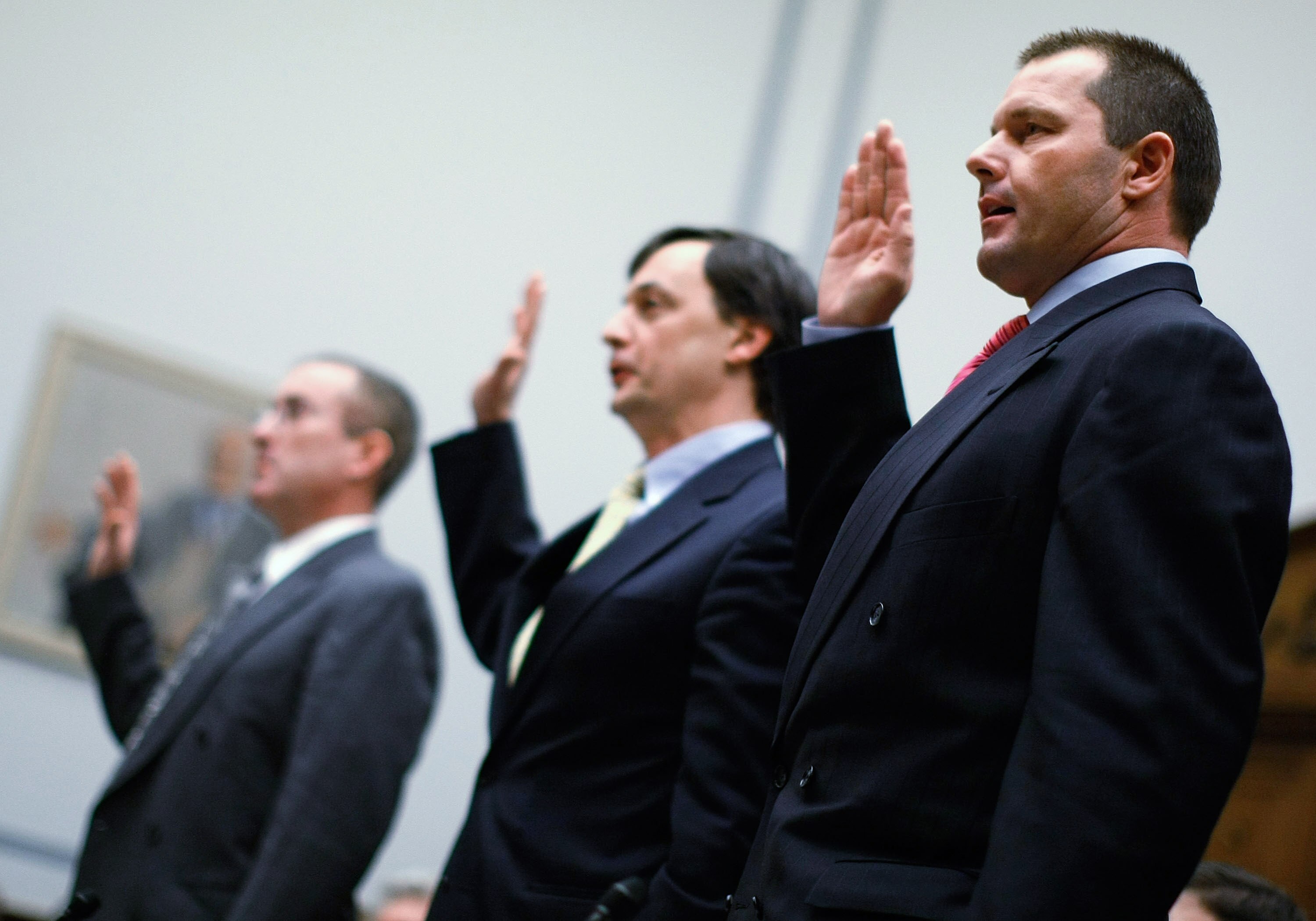WASHINGTON - FEBRUARY 13: Major League Baseball pitcher Roger Clemens (R), Charlie Scheeler, investigator on former Sen. George Mitchell's staff (C) and and former Major League Baseball strength and conditioning coach Brian McNamee (L) raise their right h