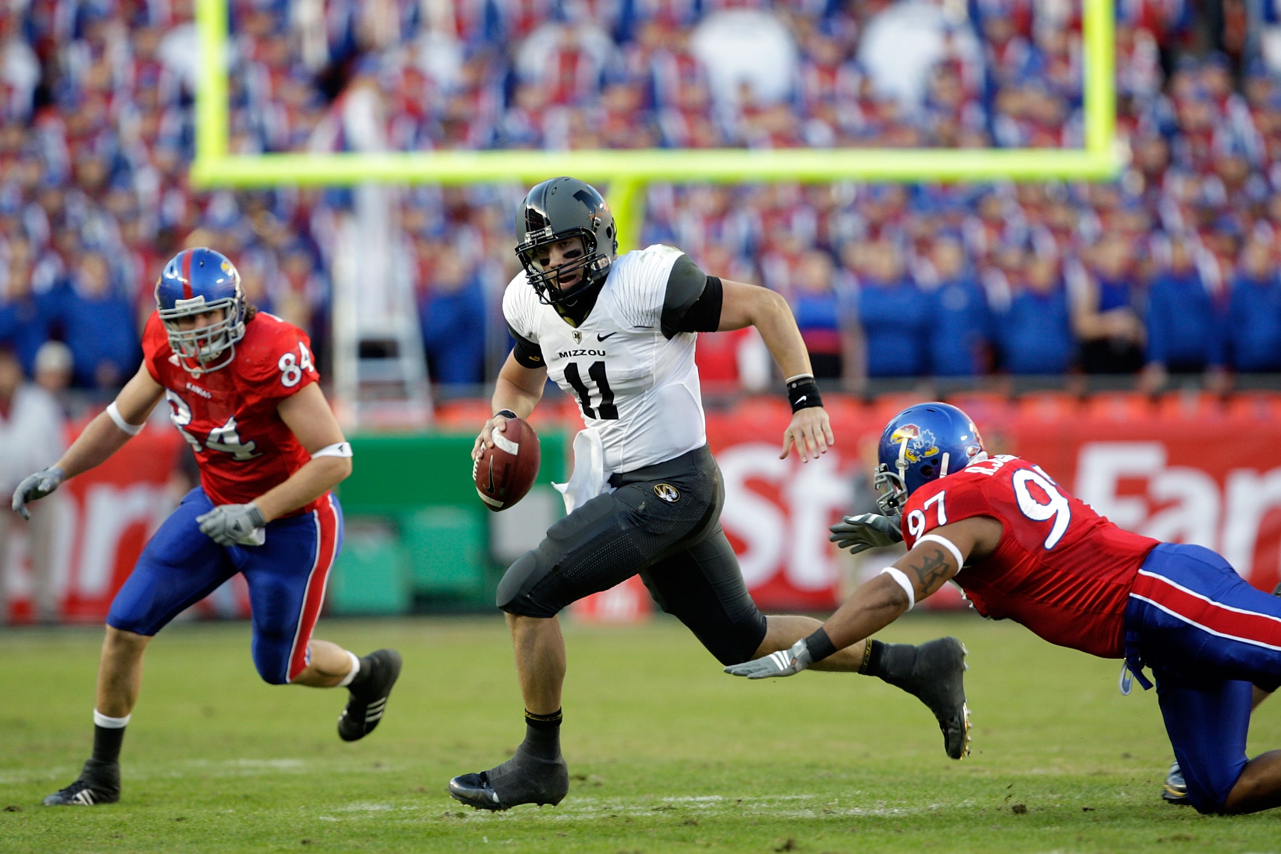 KANSAS CITY, MO - NOVEMBER 28:  Quarterback Blaine Gabbert #11 of the Missouri Tigers scrambles as Jeff Wheeler #84 and Richard Johnson Jr. #97 of the Kansas Jayhawks defend during the game at Arrowhead Stadium on November 28, 2009 in Kansas City, Missour