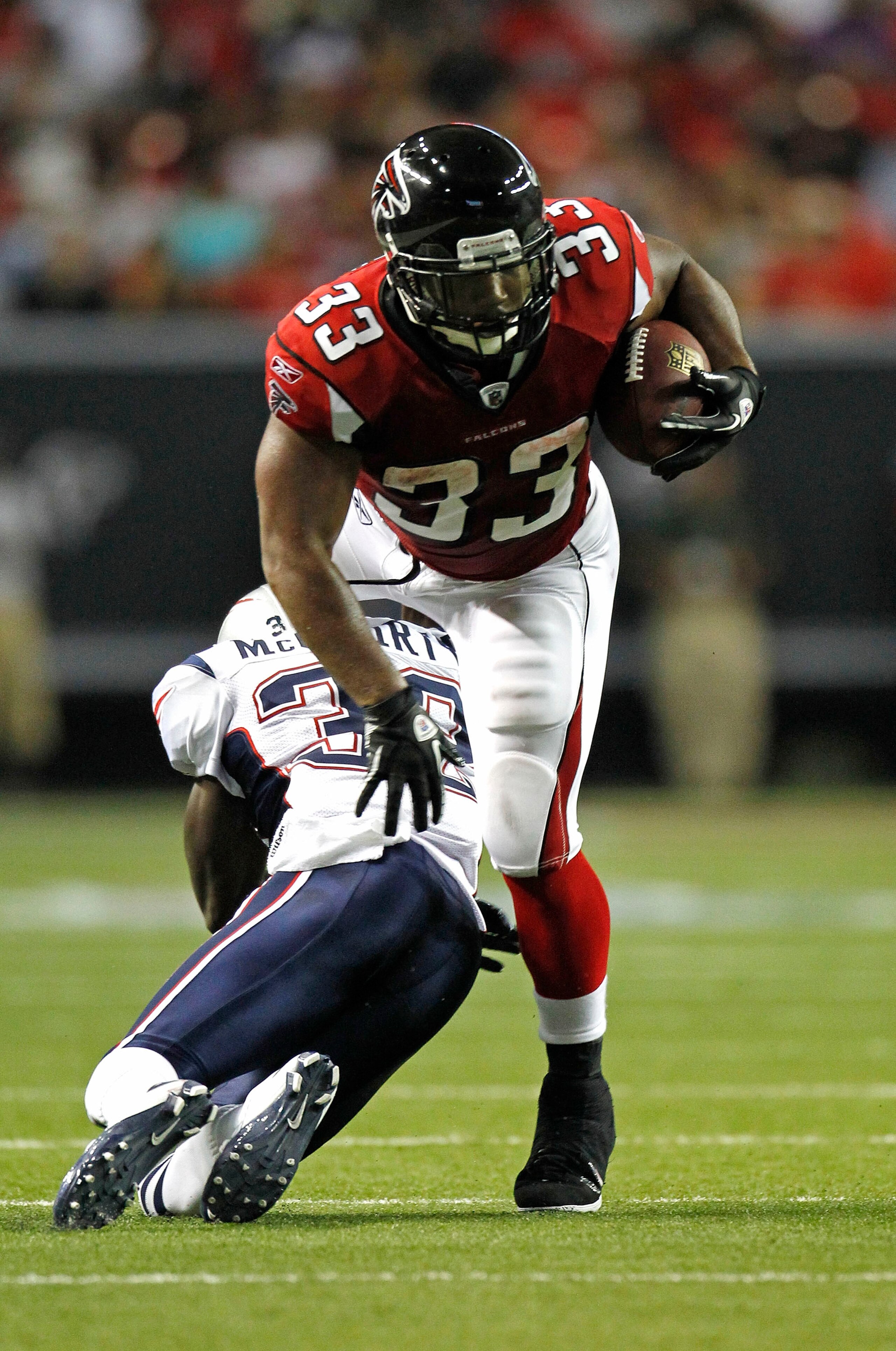 ATLANTA - AUGUST 19:  Running back Michael Turner #33 of the Atlanta Falcons is hit by cornerback Devin McCourty #32 of the New England Patriots during the preseason game at the Georgia Dome on August 19, 2010 in Atlanta, Georgia.  The Patriots beat the F