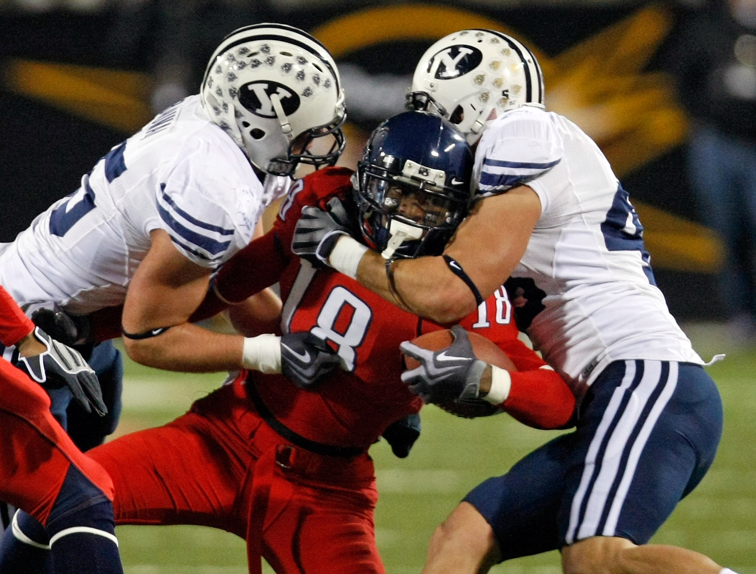 LAS VEGAS - DECEMBER 20:  Delashaun Dean #18 of the Arizona Wildcats is tackled by Matt Bauman #35 and David Nixon #43 of the Brigham Young University Cougars during the Pioneer Las Vegas Bowl at Sam Boyd Stadium December 20, 2008 in Las Vegas, Nevada.  (