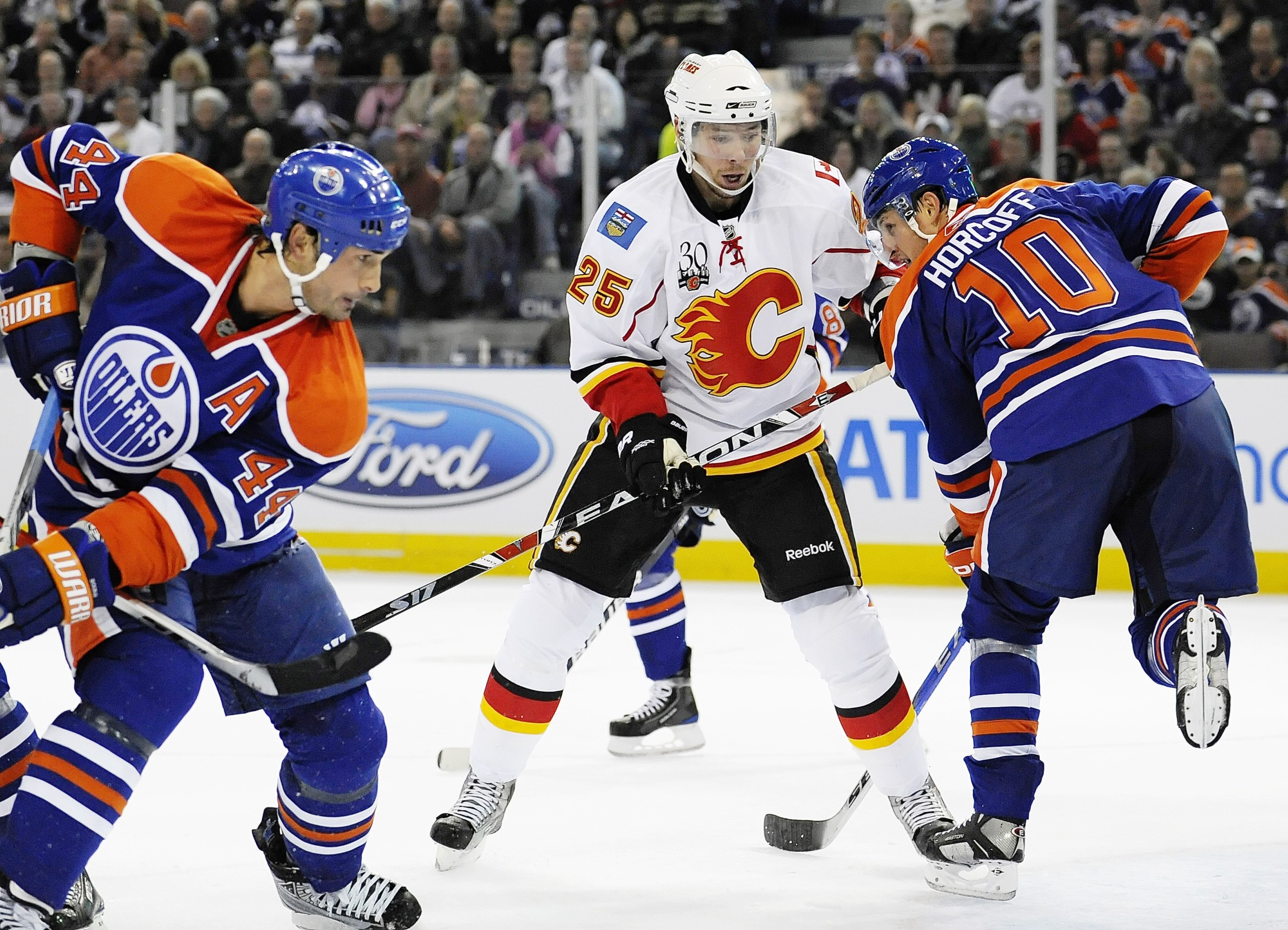 EDMONTON, AB - OCTOBER 3: David Moss #25 of the Calgary Flames skates on the ice between Sheldon Souray #44 and Shawn Horcoff #10 of the Edmonton Oilers in a game between the Calgary Flames and the Edmonton Oilers during an NHL game on October 3, 2009 at
