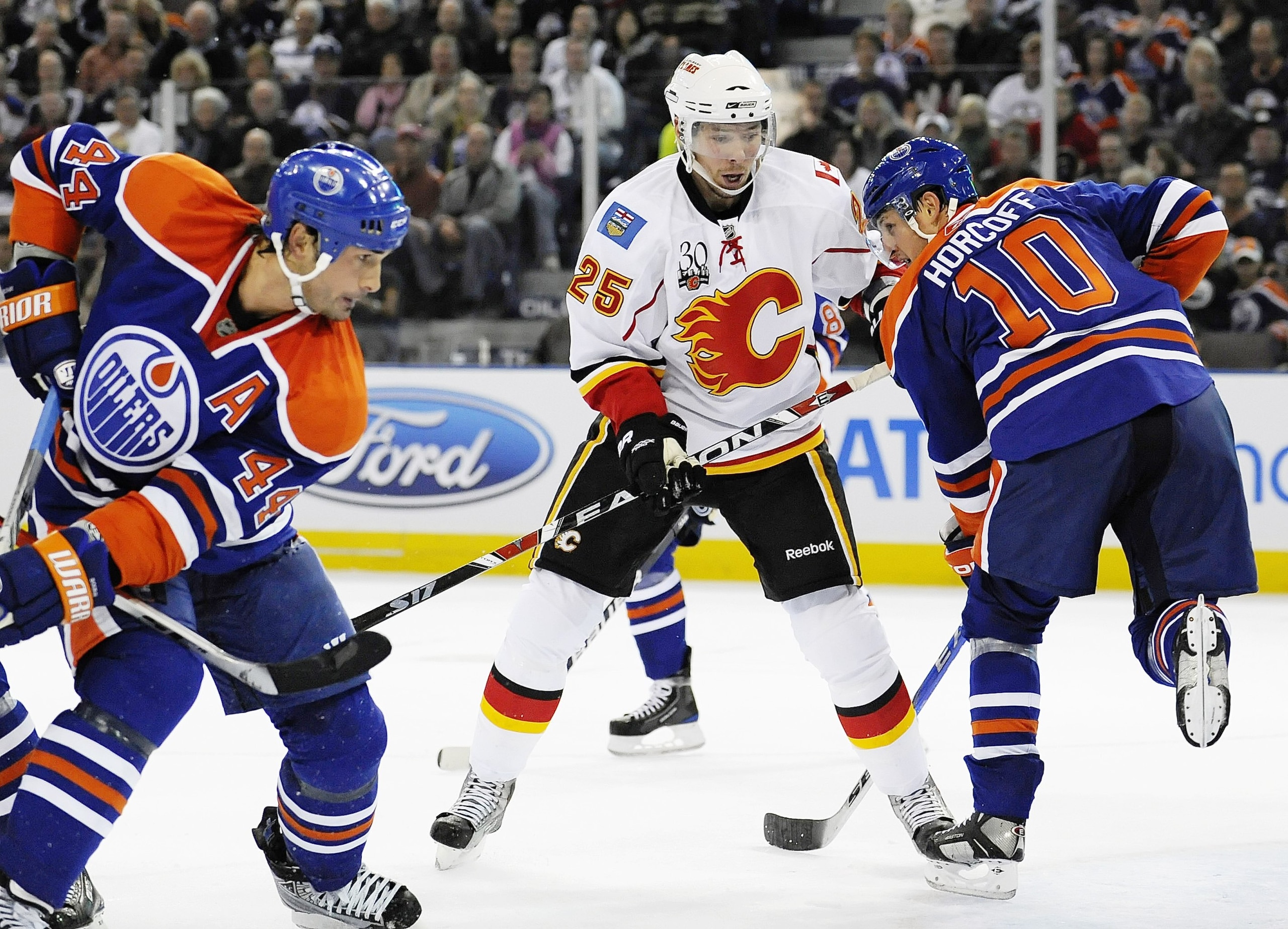 EDMONTON, AB - OCTOBER 3: David Moss #25 of the Calgary Flames skates on the ice between Sheldon Souray #44 and Shawn Horcoff #10 of the Edmonton Oilers in a game between the Calgary Flames and the Edmonton Oilers during an NHL game on October 3, 2009 at
