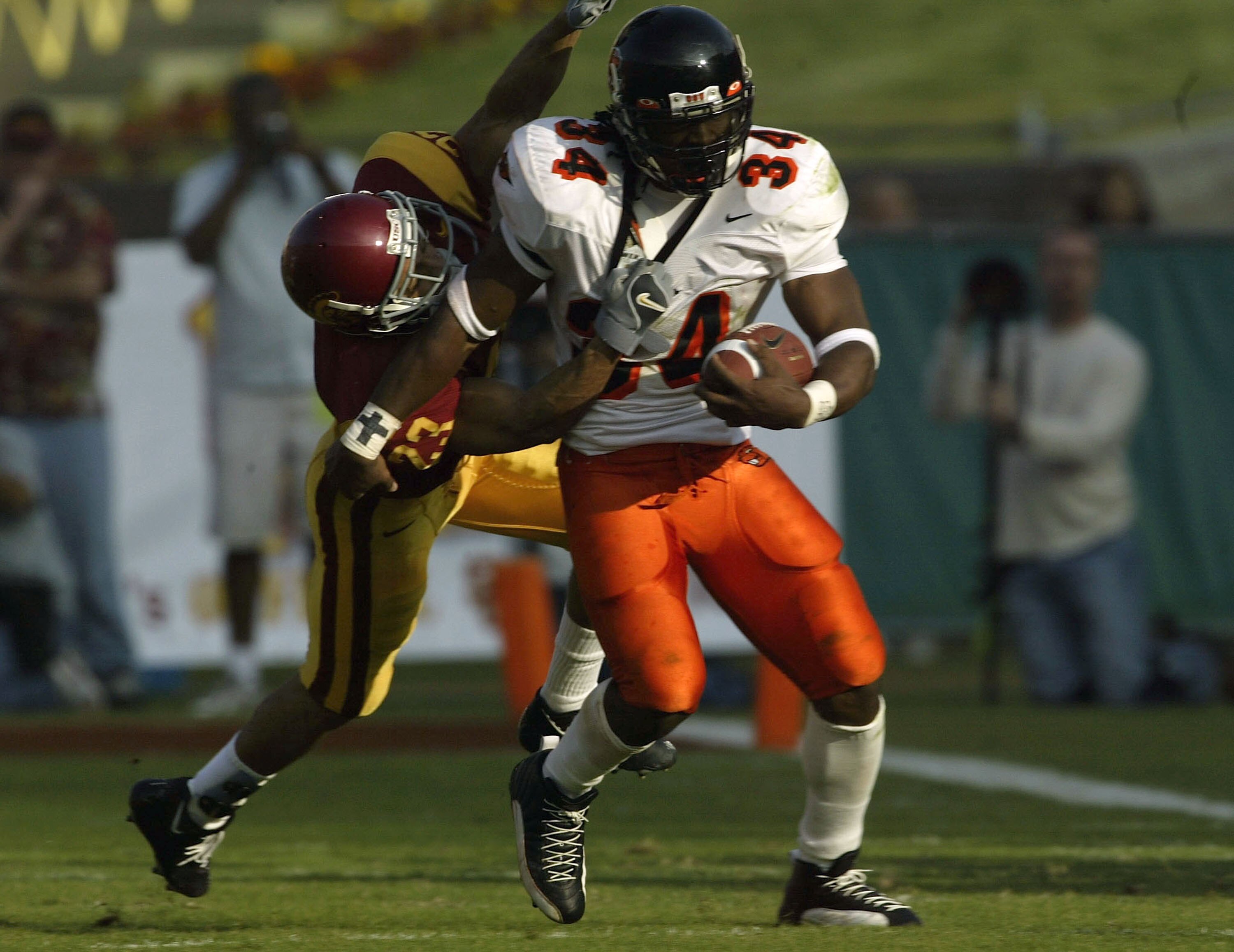 LOS ANGELES - DECEMBER 6:  Running back Steven Jackson #34 of the Oregon State Beavers carries the ball as defensive back Ronald Nunn #23 of the USC Trojans tackles him on December 6, 2003 at the Los Angeles Coliseum in Los Angeles, California.  (Photo by