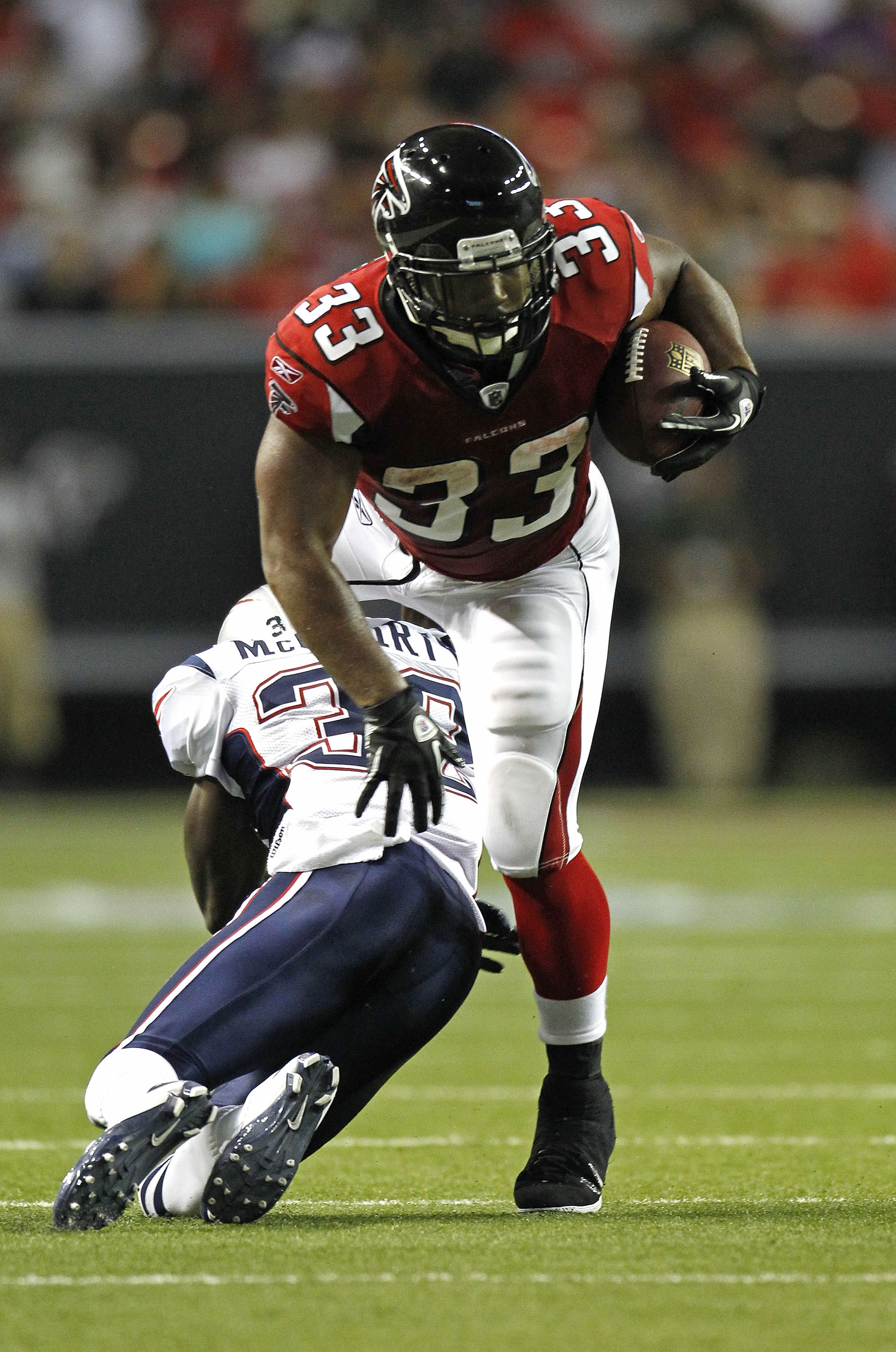 ATLANTA - AUGUST 19:  Running back Michael Turner #33 of the Atlanta Falcons is hit by cornerback Devin McCourty #32 of the New England Patriots during the preseason game at the Georgia Dome on August 19, 2010 in Atlanta, Georgia.  The Patriots beat the F