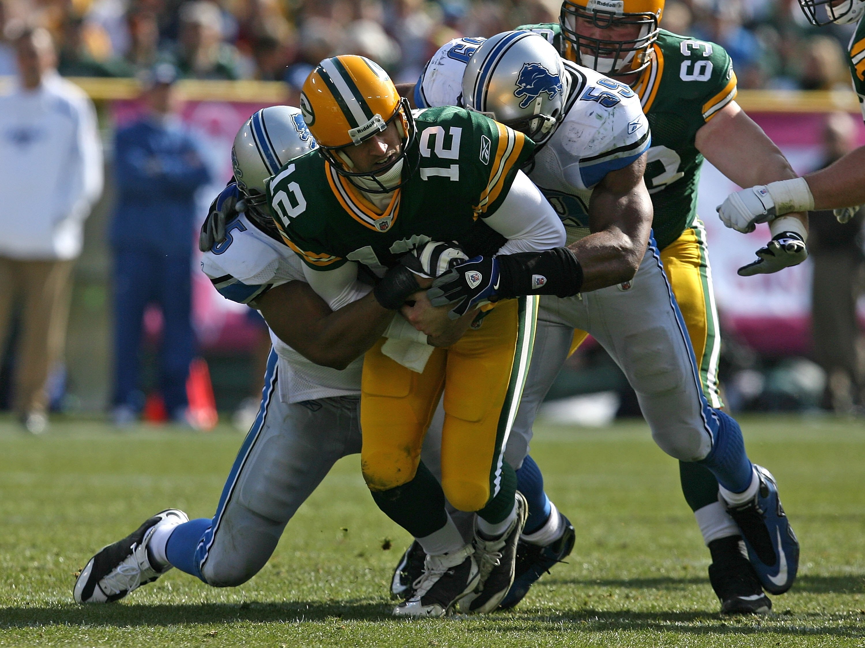 GREEN BAY, WI - OCTOBER 18: Aaron Rodgers #12 of the Green Bay Packers is sacked by Turk McBride #75 and Julian Peterson #59 of Detroit Lions at Lambeau Field on October 18, 2009 in Green Bay, Wisconsin. The Packers defeated the Lions 26-0. (Photo by Jona