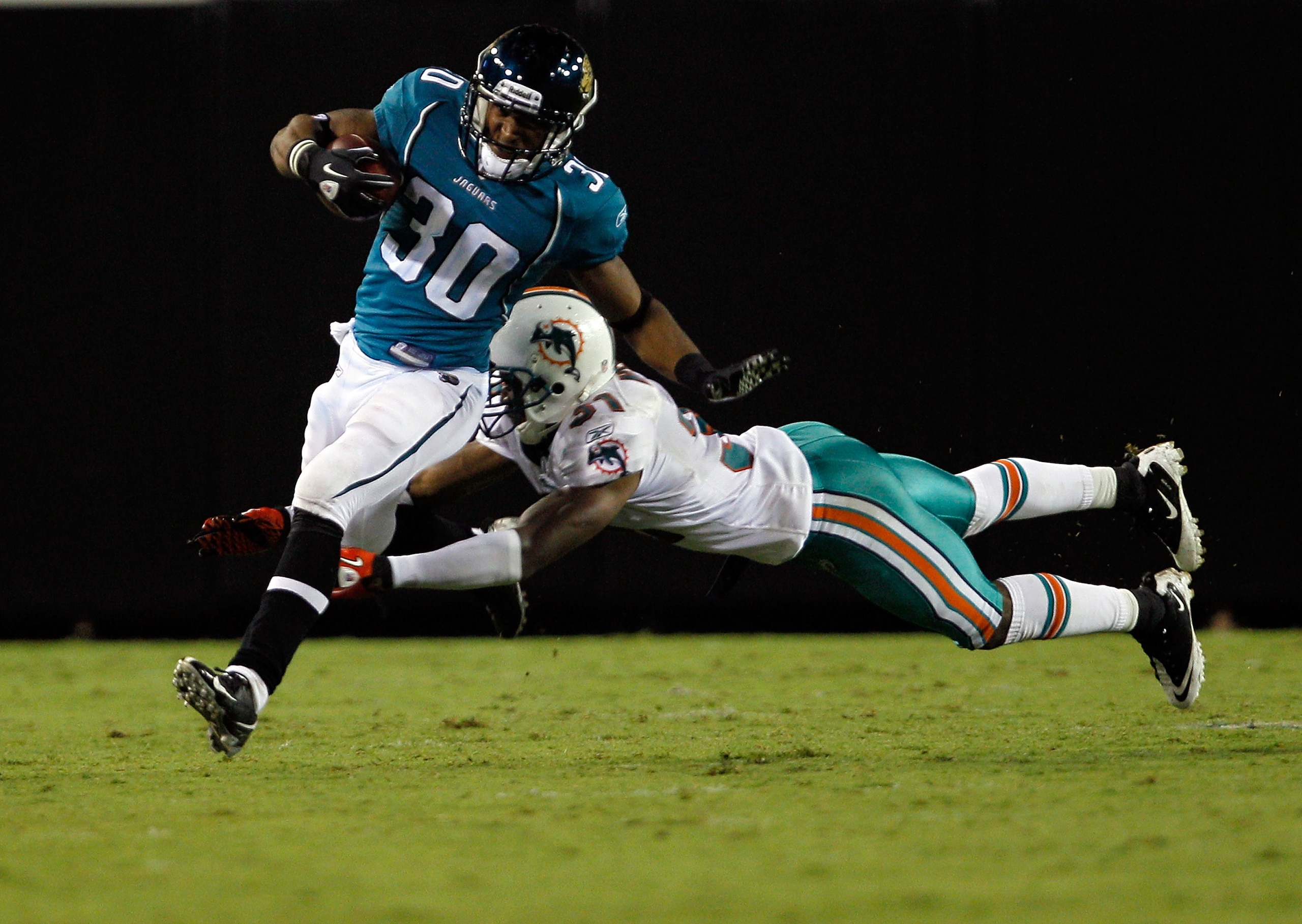 JACKSONVILLE, FL - AUGUST 21:  Nate Ness #31 of the Miami Dolphins attempts to tackle Scotty McGee #30 of the Jacksonville Jaguars during the preseason game at EverBank Field on August 21, 2010 in Jacksonville, Florida.  (Photo by Sam Greenwood/Getty Imag