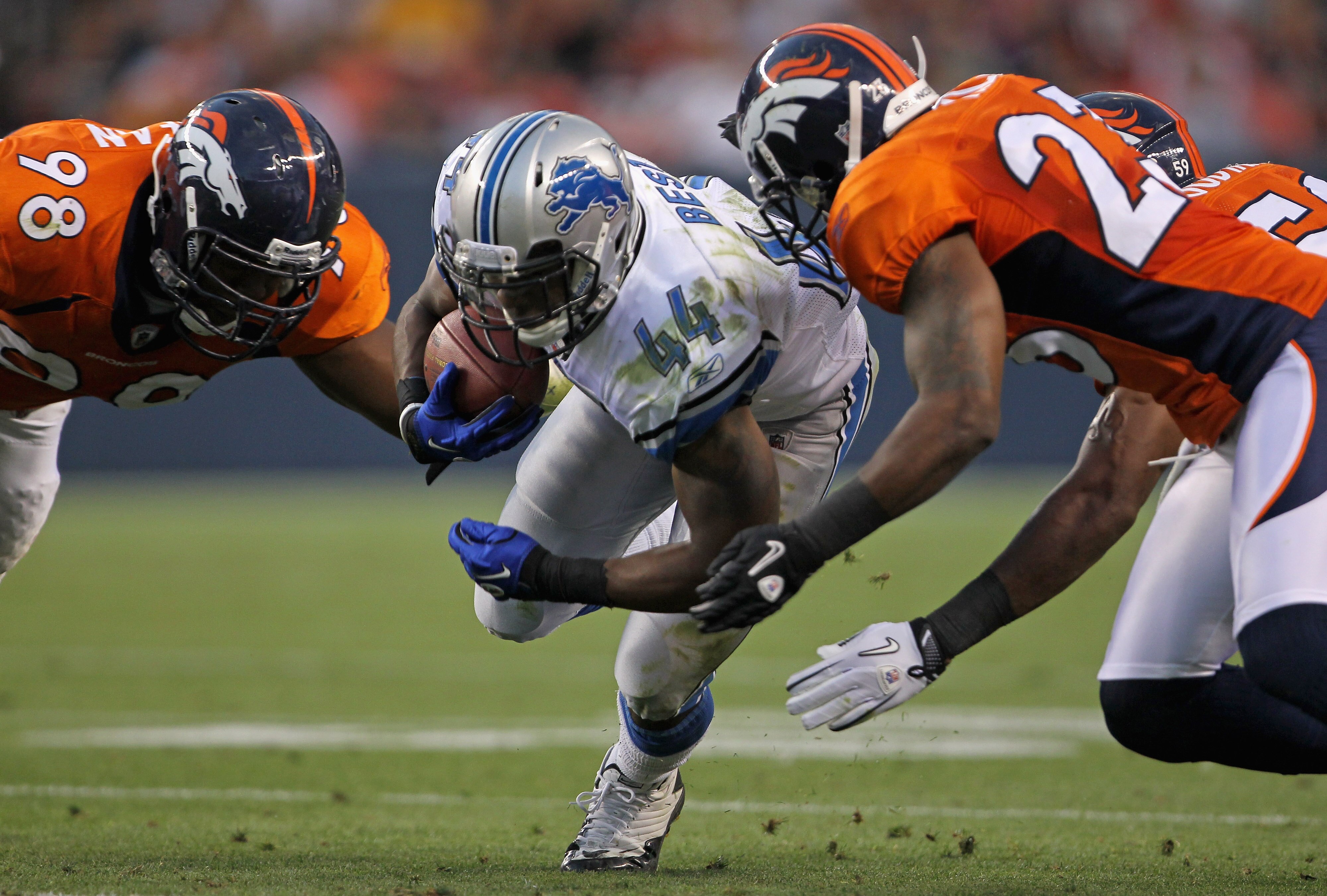 DENVER - AUGUST 21:  Jahvid Best #44 of the Detroit Lions rushes the ball as Ryan McBean #98 and Renaldo Hill #23 of the Denver Broncos make the stop during preseason NFL action at INVESCO Field at Mile High on August 21, 2010 in Denver, Colorado. The tou