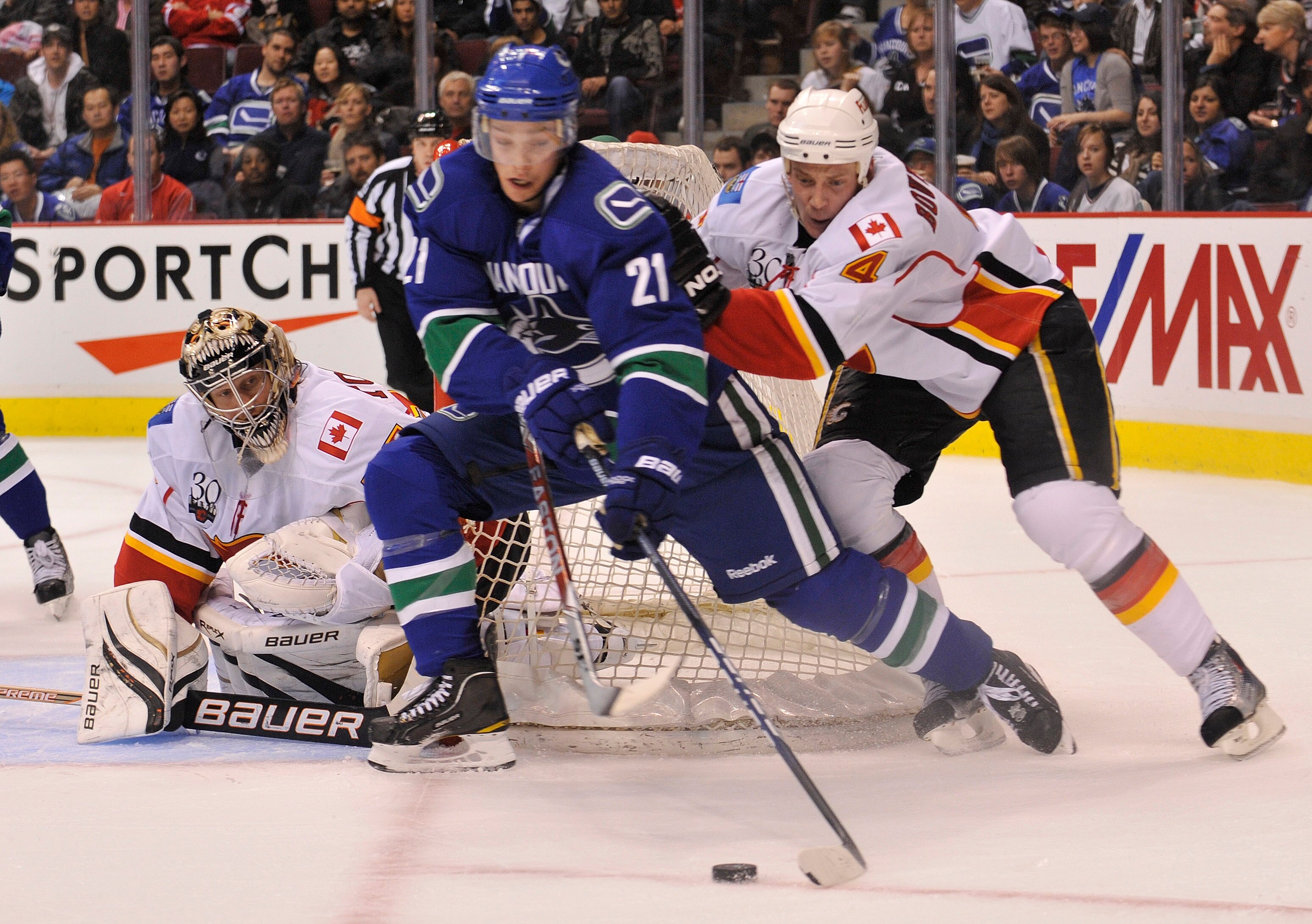 VANCOUVER, CANADA - MARCH 14: Goalie Vesa Toskala #35 of the Calgary Flames keeps an eye on Mason Raymond #21 of the Vancouver Canucks as he comes from behind the net while being checked by Flames Jay Bouwmeester #4 during the second period of NHL action