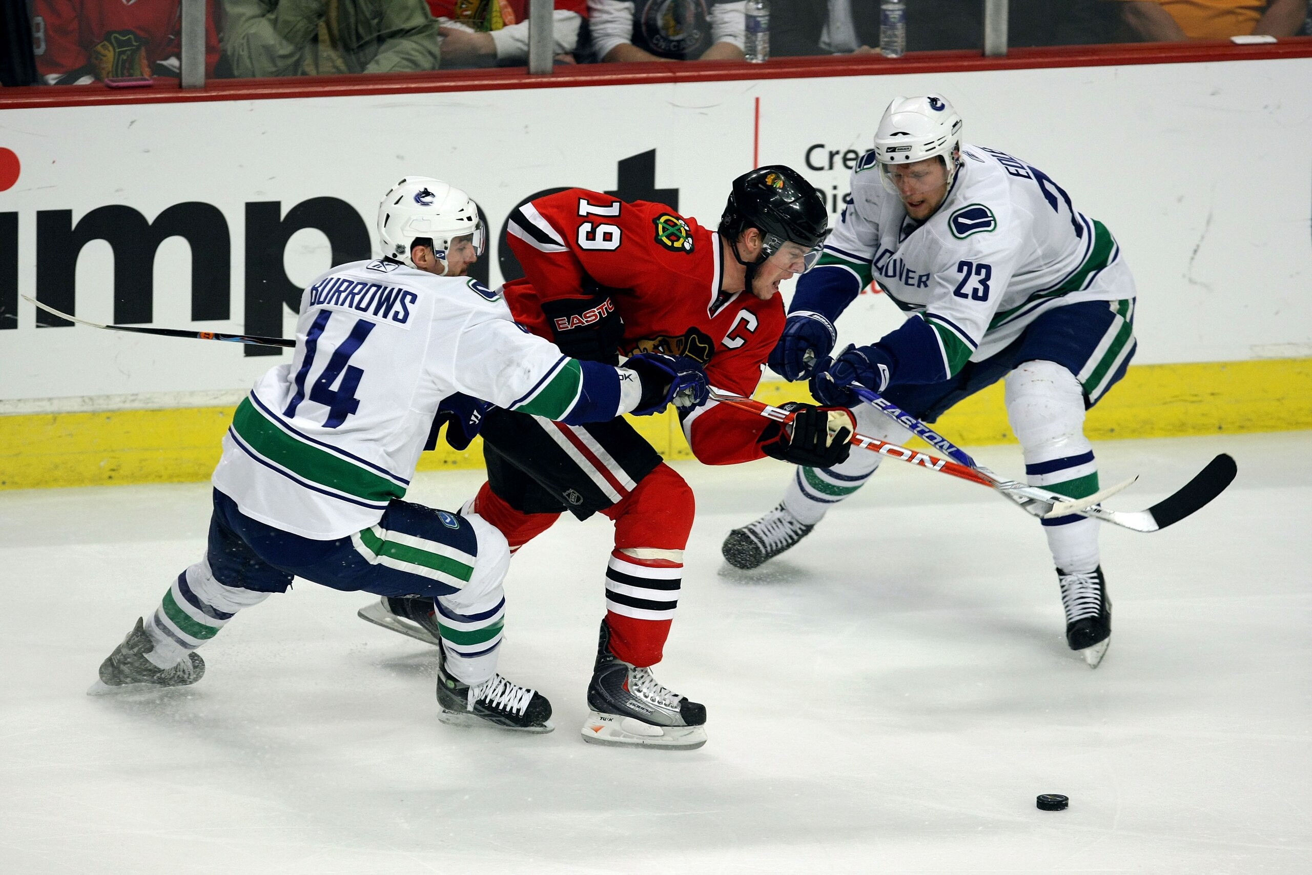 CHICAGO - MAY 11: Jonathan Toews #19 of the Chicago Blackhawks fights for the puck against Alex Burrows #14 and Alexander Edler #23 of the Vancouver Canucks during Game Six of the Western Conference Semifinal Round of the 2009 Stanley Cup Playoffs on May CHICAGO - MAY 11: Jonathan Toews #19 of the Chicago Blackhawks fights for the puck against Alex Burrows #14 and Alexander Edler #23 of the Vancouver Canucks during Game Six of the Western Conference Semifinal Round of the 2009 Stanley Cup Playoffs on May