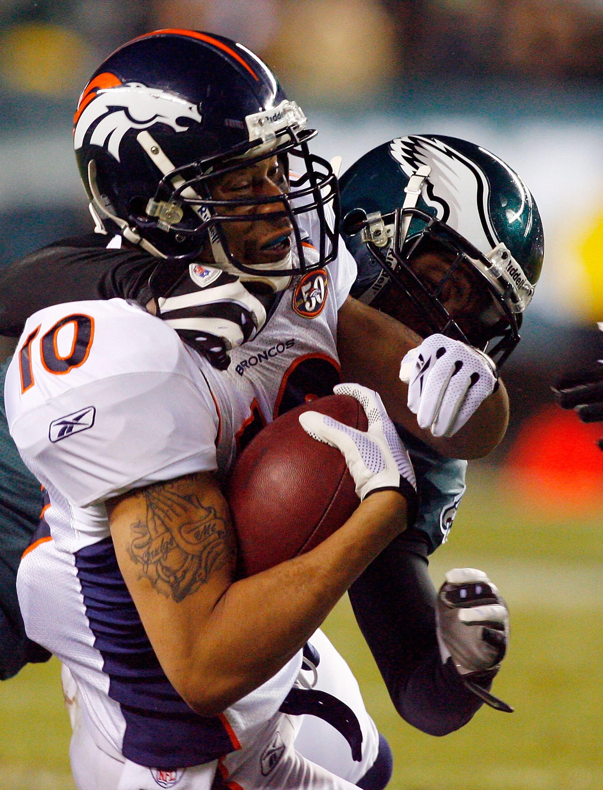 PHILADELPHIA - DECEMBER 27:  Asante Samuel #22 of the Philadelphia Eagles tackles Jabar Gaffney #10 of the Denver Broncos on December 27, 2009 at Lincoln Financial Field in Philadelphia, Pennsylvania. The Eagles defeated the Broncos 30-27.  (Photo by Jim