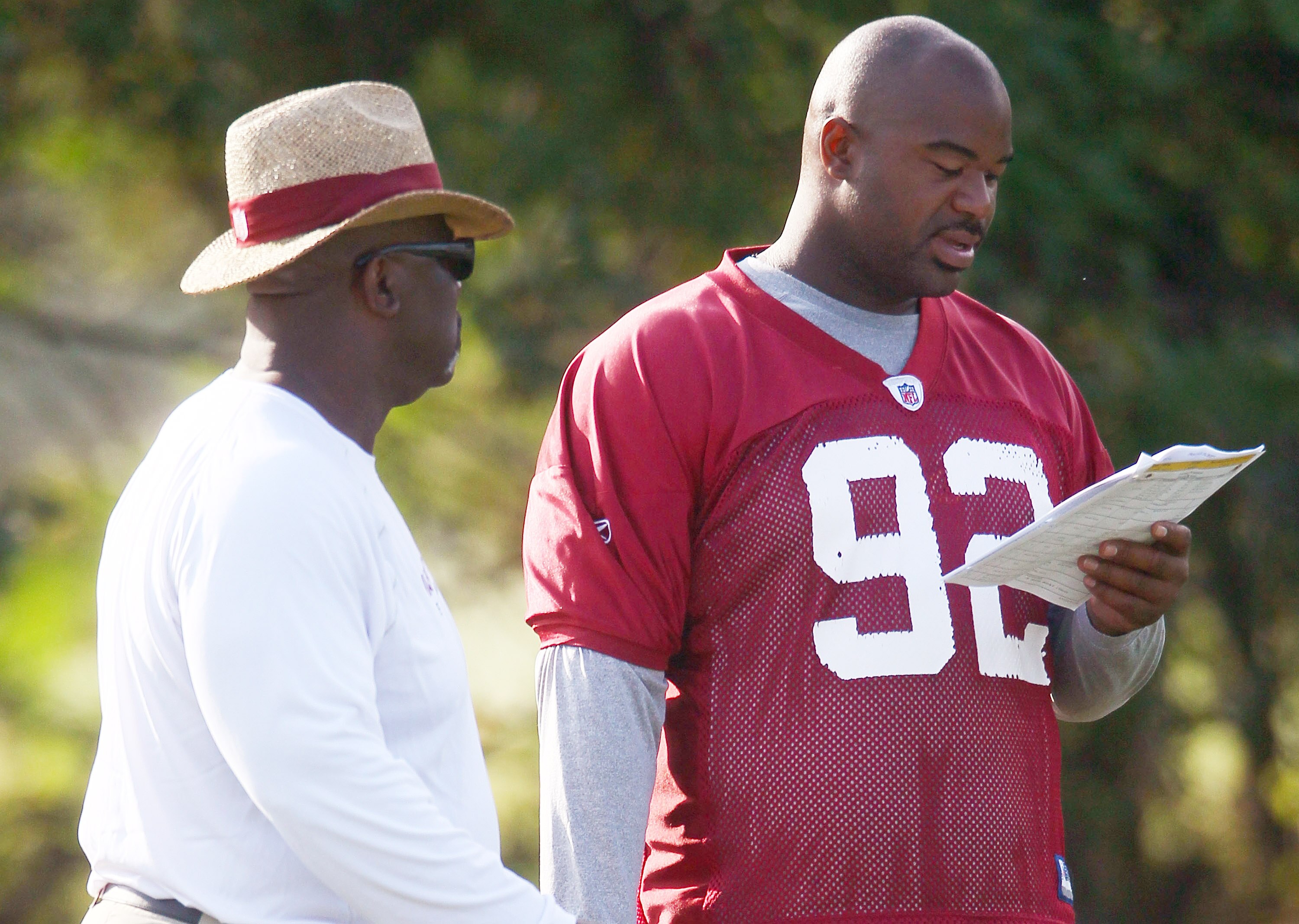 ASHBURN, VA - AUGUST 06:  Defensive lineman Albert Haynesworth #92 of the Washington Redskins reviews his assignments with defensive line coach Jacob Burney (L) as he sits out his eighth consecutive day of practice during Redskins training camp on August 