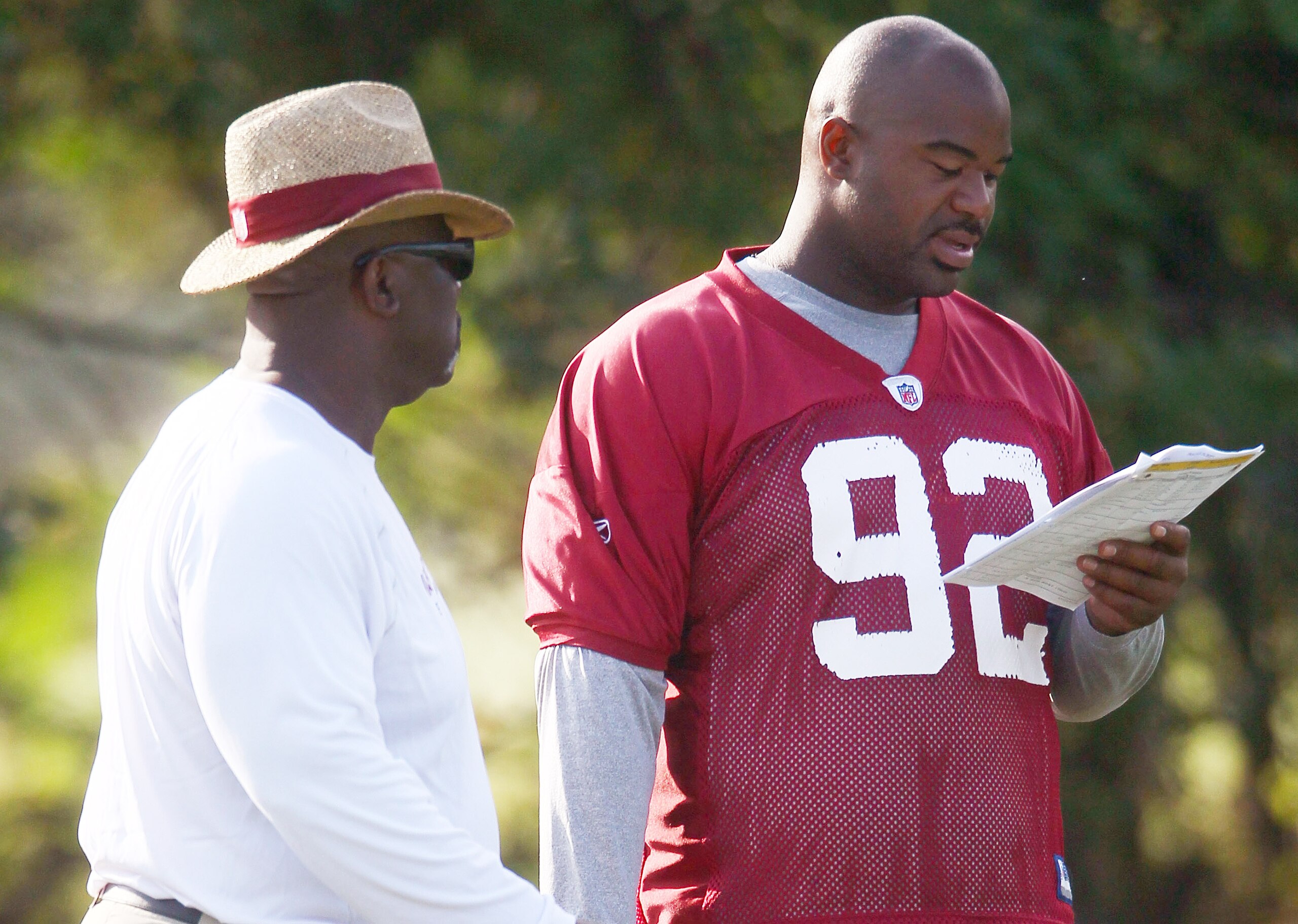 ASHBURN, VA - AUGUST 06:  Defensive lineman Albert Haynesworth #92 of the Washington Redskins reviews his assignments with defensive line coach Jacob Burney (L) as he sits out his eighth consecutive day of practice during Redskins training camp on August 
