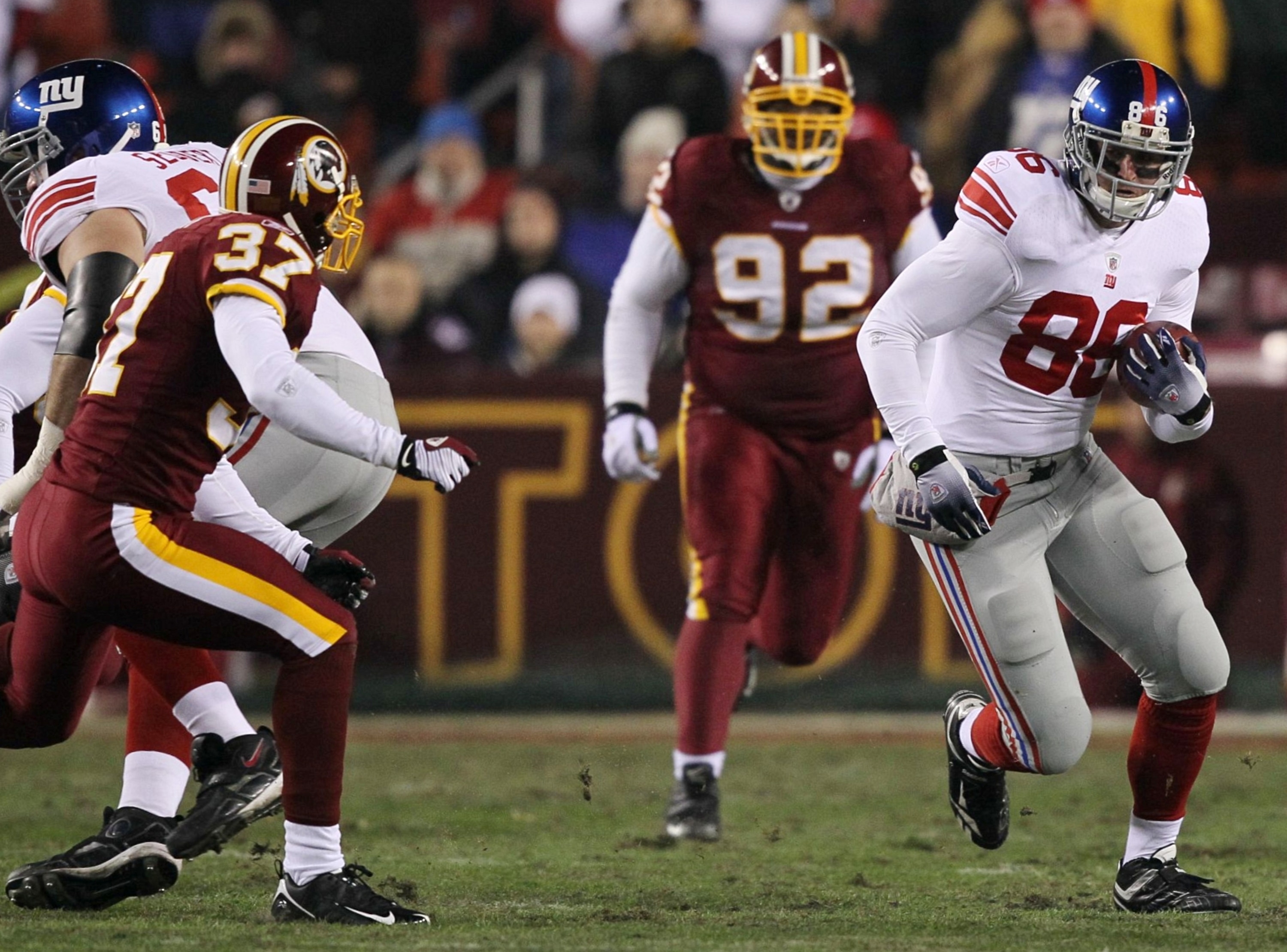 LANDOVER, MD - DECEMBER 21:  Tight end Bear Pascoe #86 of the New York Giants runs after-the-catch for nine-yards before being tackled by Reed Doughty #37 of the Washington Redskins in the first quarter at FedEx Field on December 21, 2009 in Landover, Mar