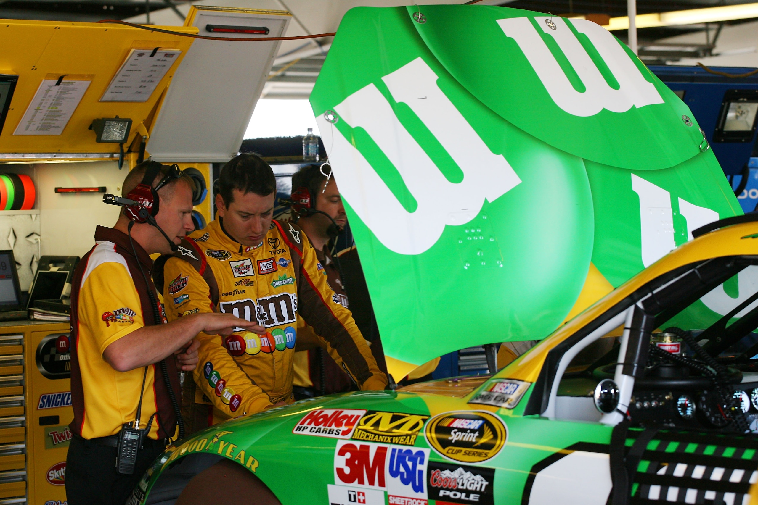 WATKINS GLEN, NY - AUGUST 06:  Kyle Busch (R), driver of the #18 M&M's Toyota, talks with his crew chief Dave Rogers in the garage during practice for the NASCAR Heluva Good! Sour Cream Dips at The Glen on August 6, 2010 in Watkins Glen, New York.  (Photo