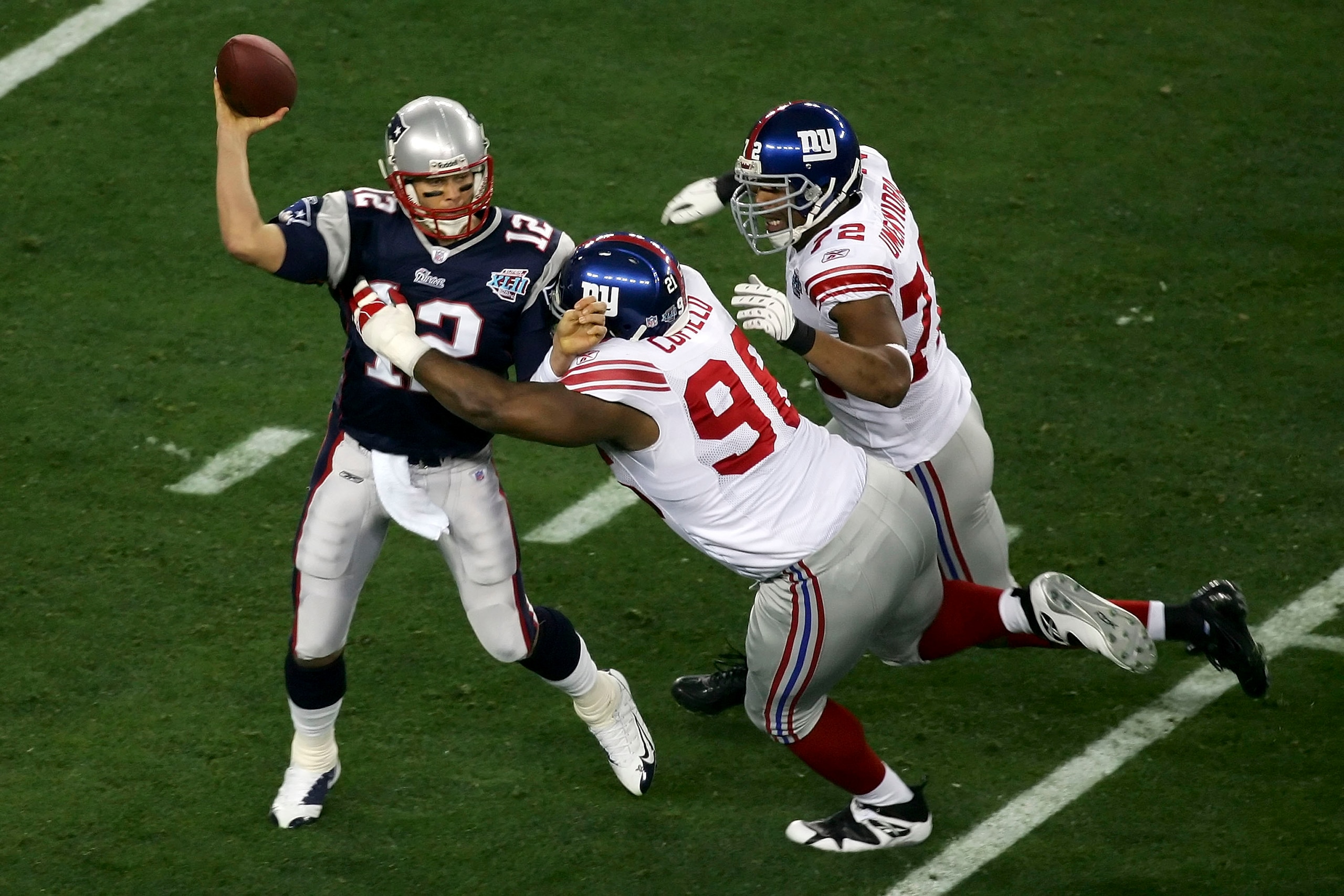 GLENDALE, AZ - FEBRUARY 03:  Quarterback Tom Brady #12 of the New England Patriots is hit as he throws by defensive tackle Barry Cofield #96 and Osi Umenyiora #72 of the New York Giants in the first half during Super Bowl XLII on February 3, 2008 at the U