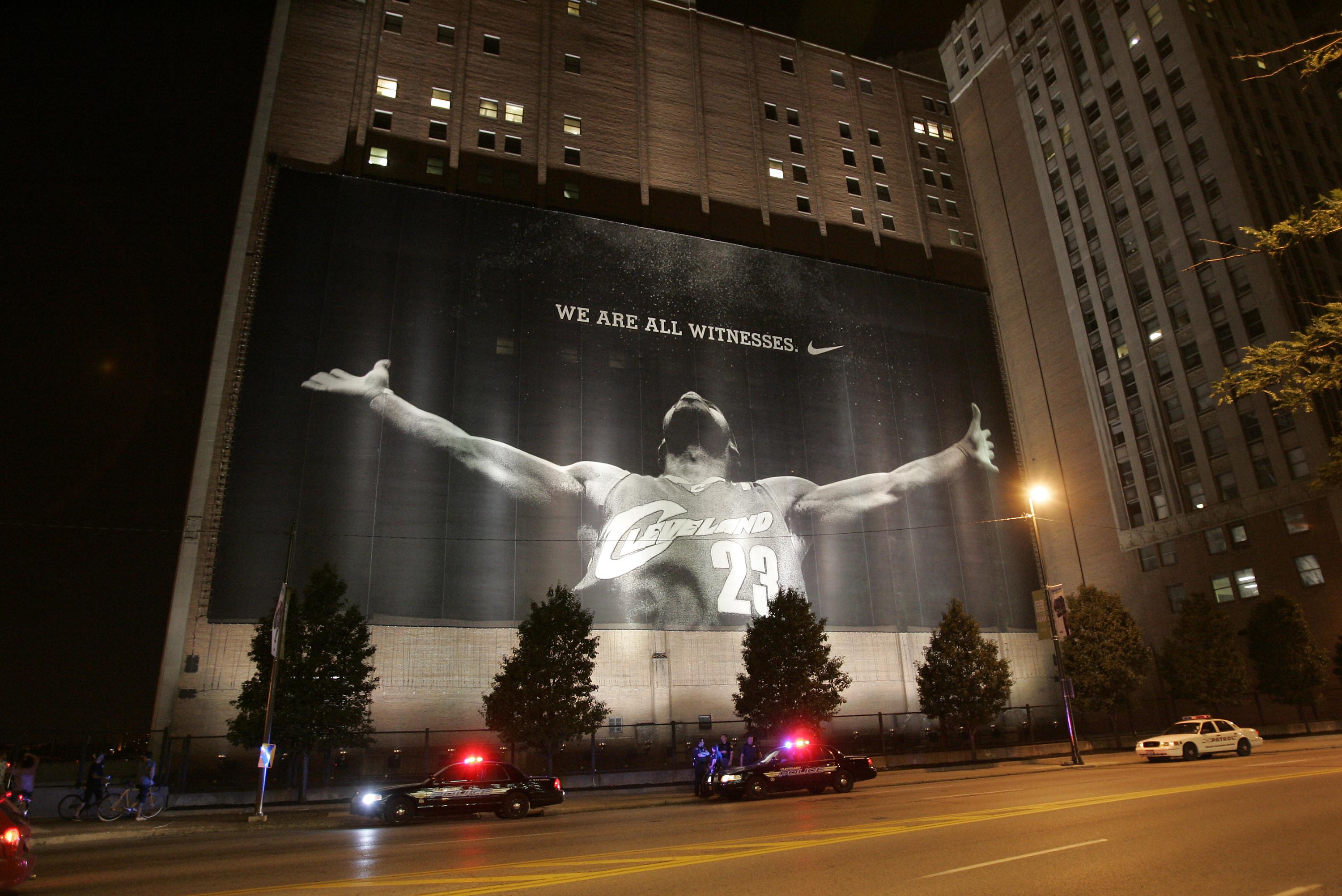 CLEVELAND - JULY 8:  Police stand guard near a larger than life photograph of LeBron James after the announcement that James will play next season for the Miami Heat July 8, 2010 in Cleveland, Ohio. The two-time Most Valuable Player made the choice to pla