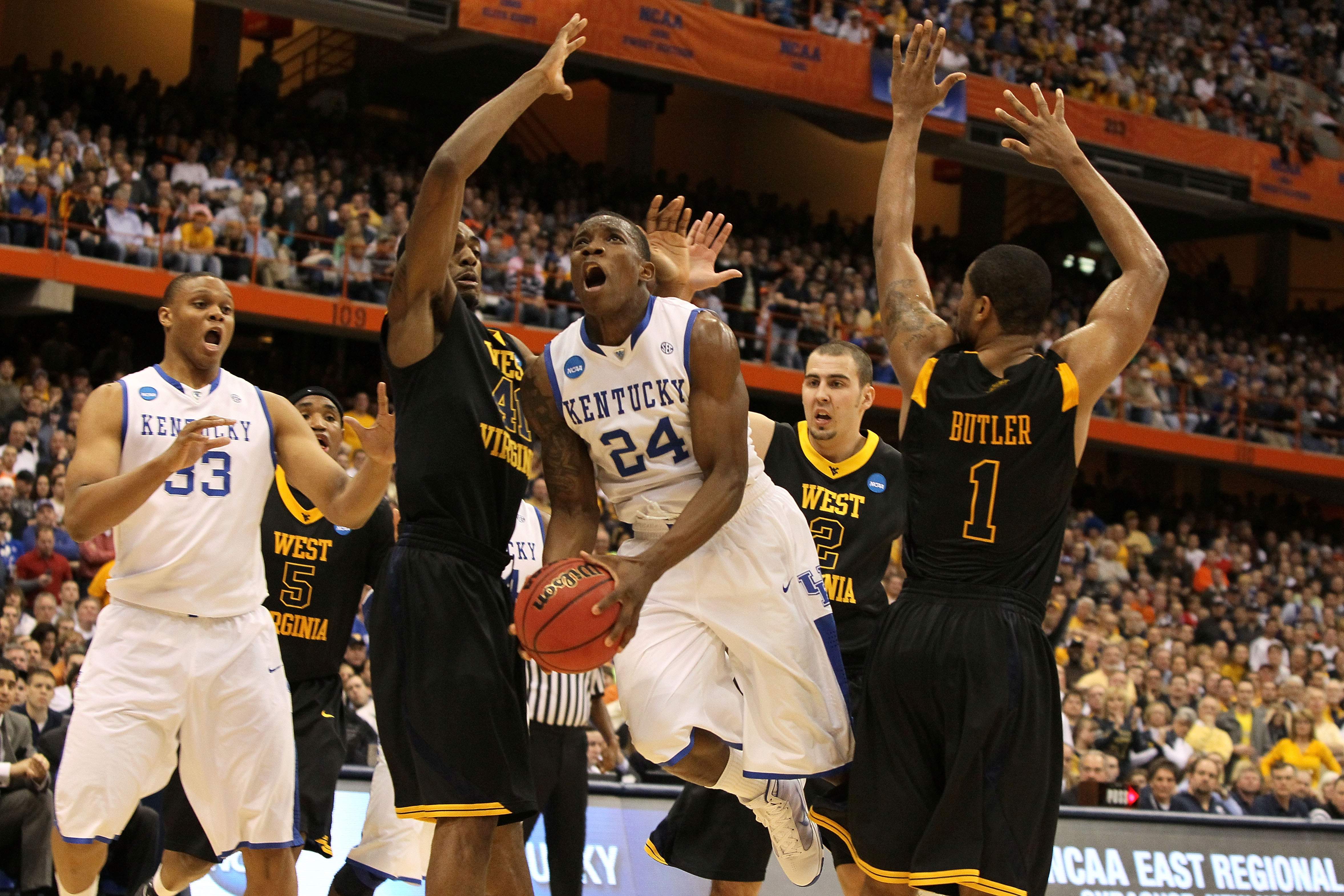 SYRACUSE, NY - MARCH 27:  Eric Bledsoe #24 of the Kentucky Wildcats drives for a shot attempt against John FLowers #41 and Da'Sean Butler #1 of the West Virginia Mountaineers during the east regional final of the 2010 NCAA men's basketball tournament at t
