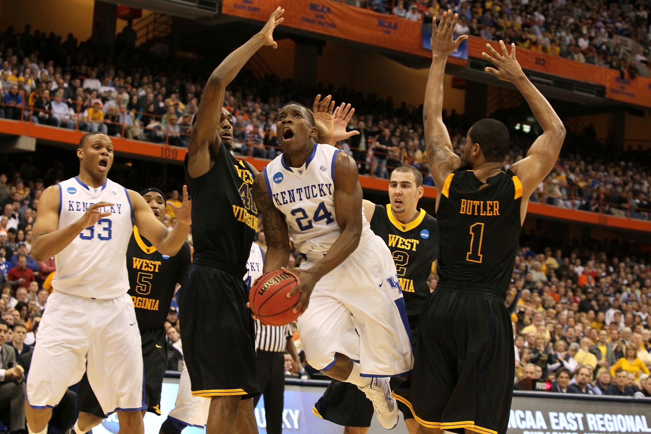 SYRACUSE, NY - MARCH 27:  Eric Bledsoe #24 of the Kentucky Wildcats drives for a shot attempt against John FLowers #41 and Da'Sean Butler #1 of the West Virginia Mountaineers during the east regional final of the 2010 NCAA men's basketball tournament at t