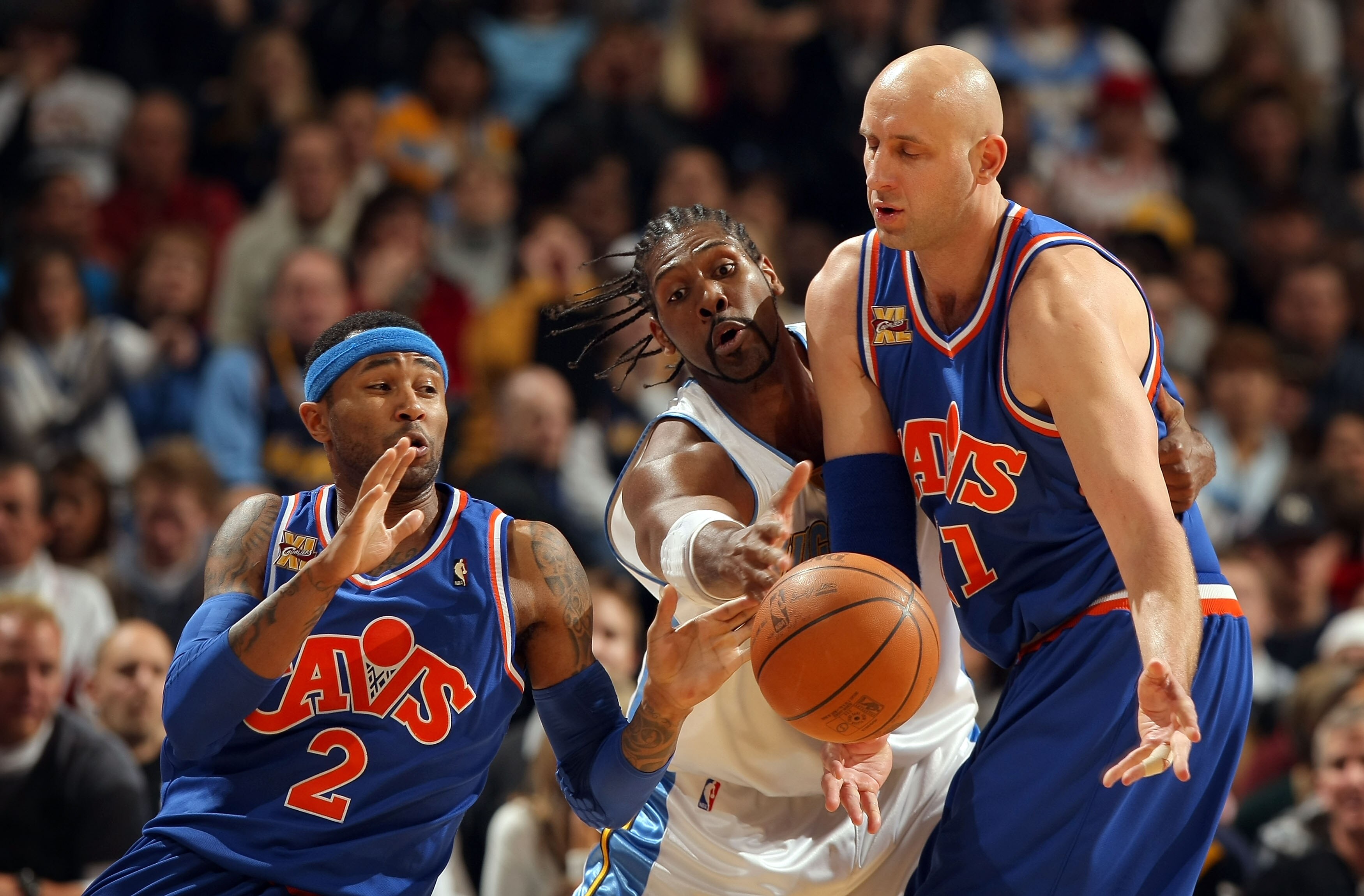 DENVER - JANUARY 08:  Zydrunas Ilgauskas #11 of the Cleveland Cavaliers dishes off the ball to Mo Williams #2 as Nene #31 of the Denver Nuggets defends during NBA action at Pepsi Center on January 8, 2010 in Denver, Colorado. The Nuggets defeated the Cava