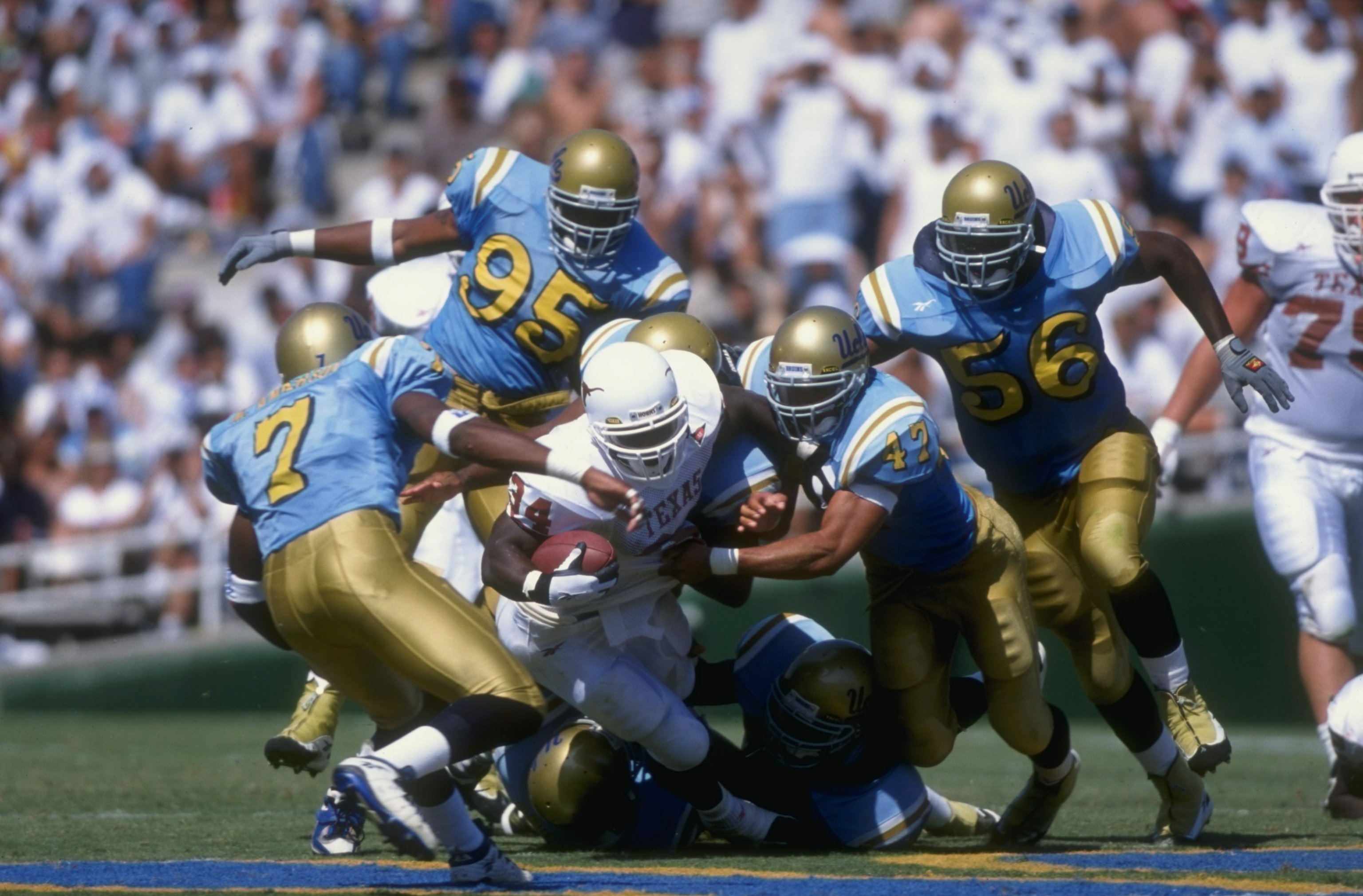12 Sep 1998: Ricky Williams #34 of the Texas Longhorns grips the ball as he is tackled during the game against the UCLA Bruins at the Rose Bowl in Pasadena, California. UCLA defeated Texas 49-31.