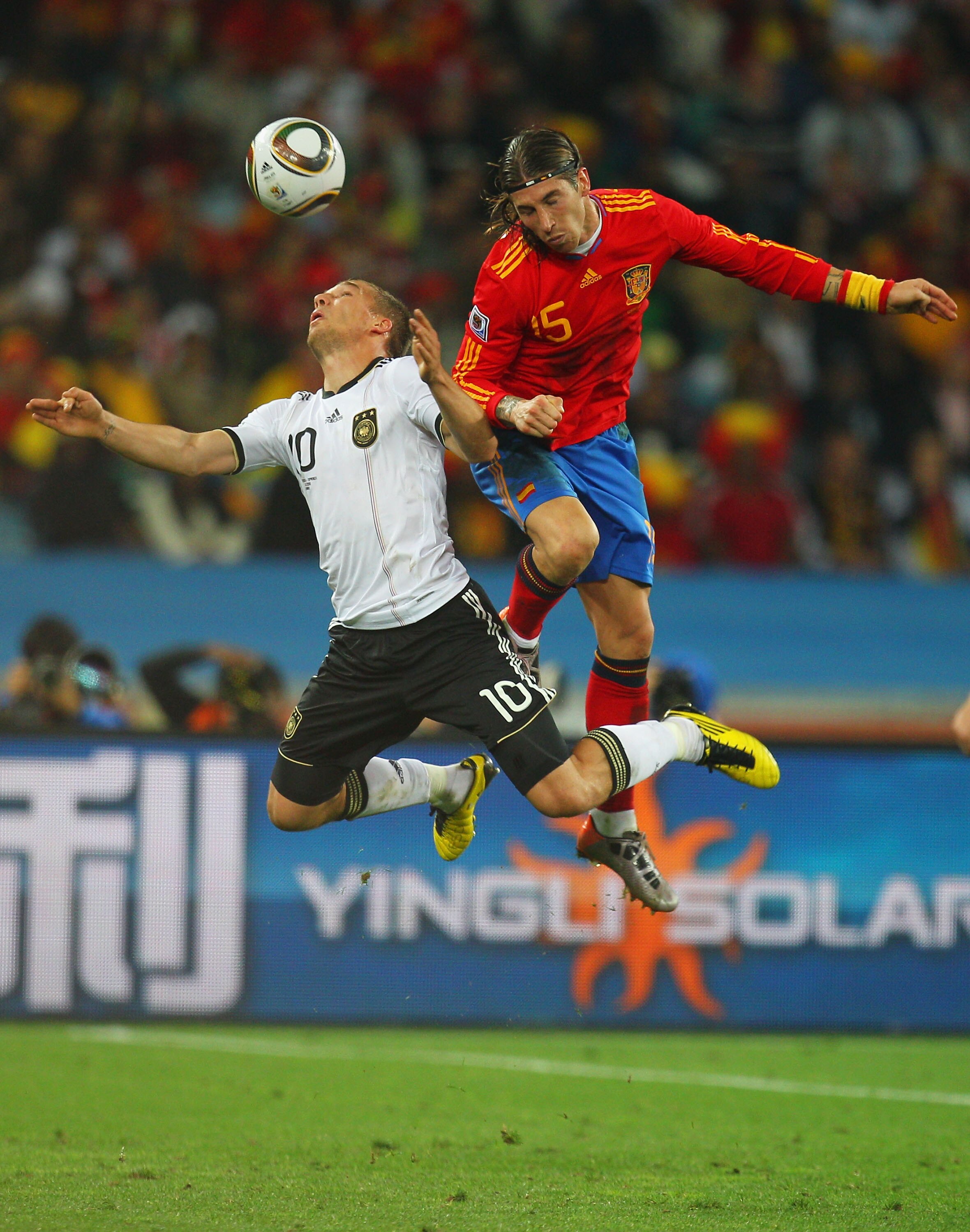 DURBAN, SOUTH AFRICA - JULY 07:  Lukas Podolski of Germany and Sergio Ramos of Spain go up for the ball during the 2010 FIFA World Cup South Africa Semi Final match between Germany and Spain at Durban Stadium on July 7, 2010 in Durban, South Africa.  (Pho